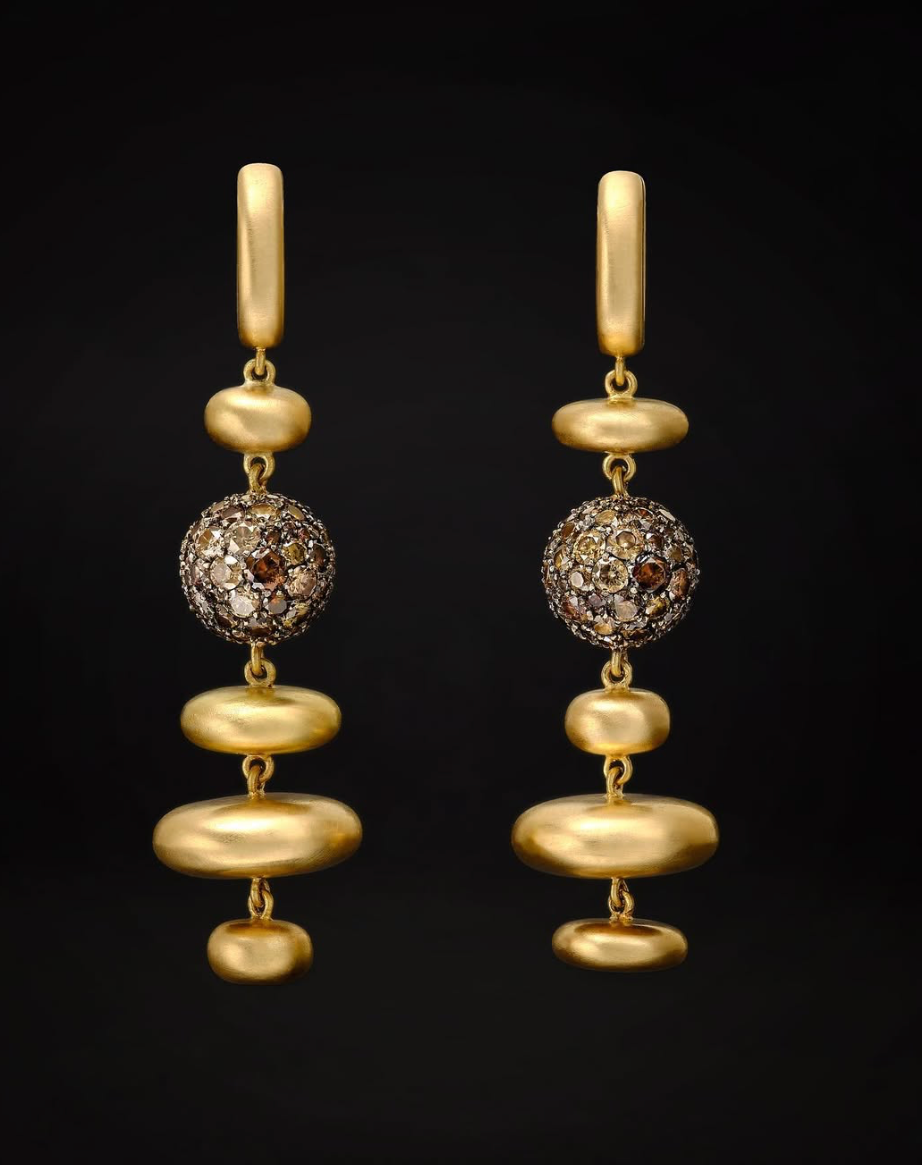 Pair of gold drop earrings with jewelled spheres set against black