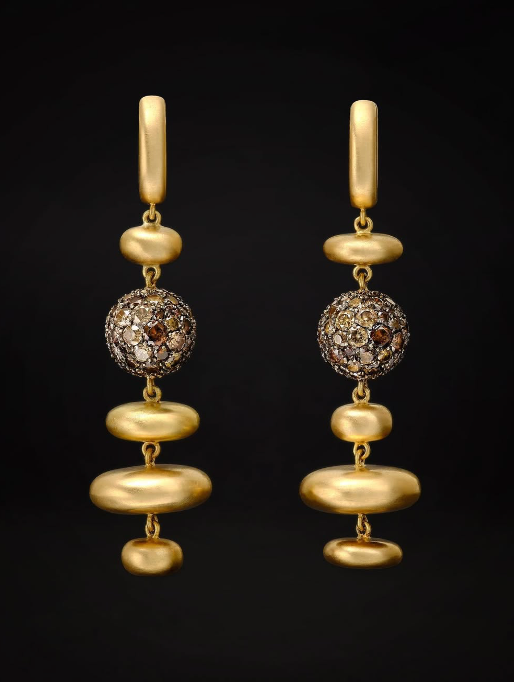 Pair of gold drop earrings with jewelled spheres set against black