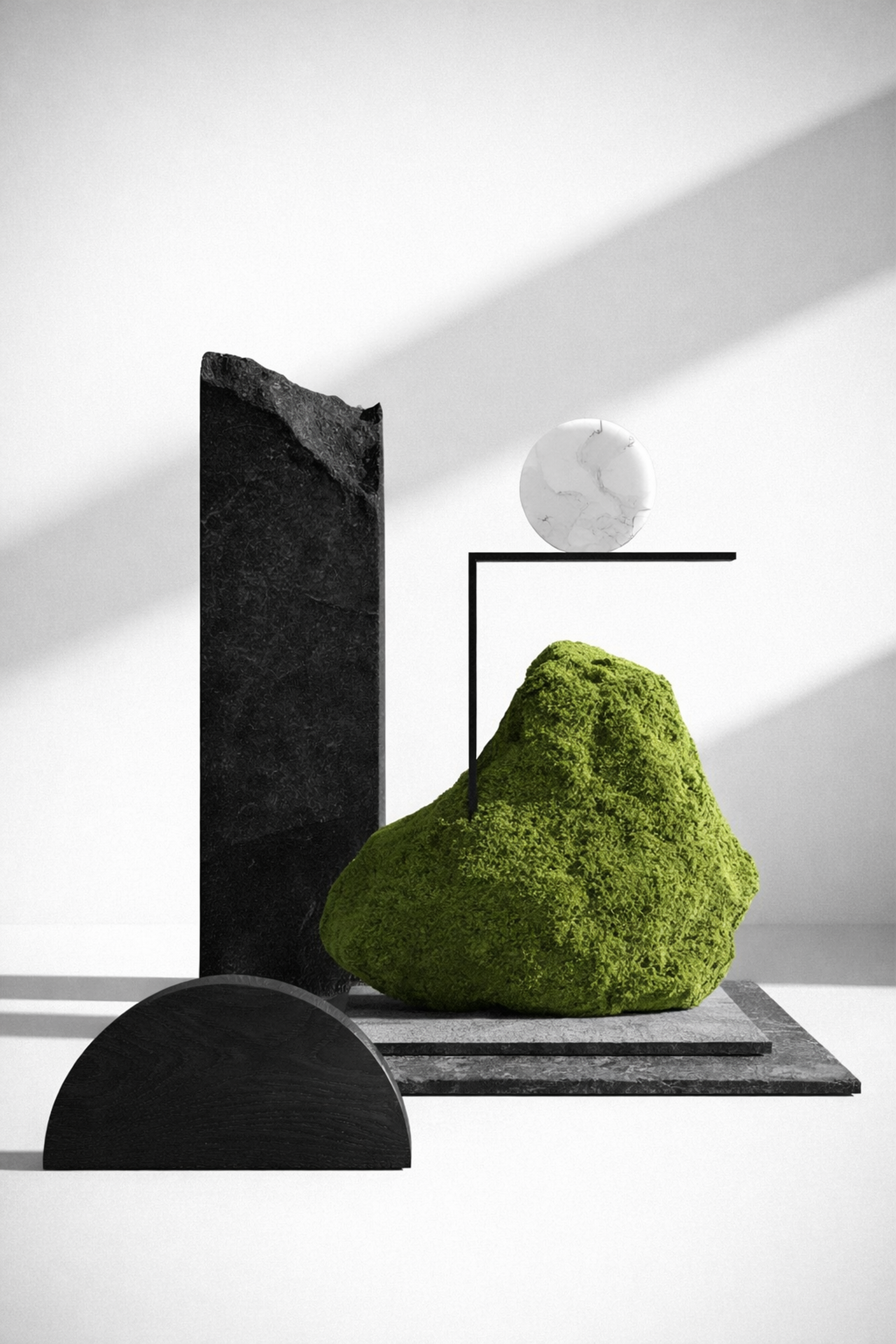 Still-life study of blackened stone, a mossy boulder and a pale sphere in raking light