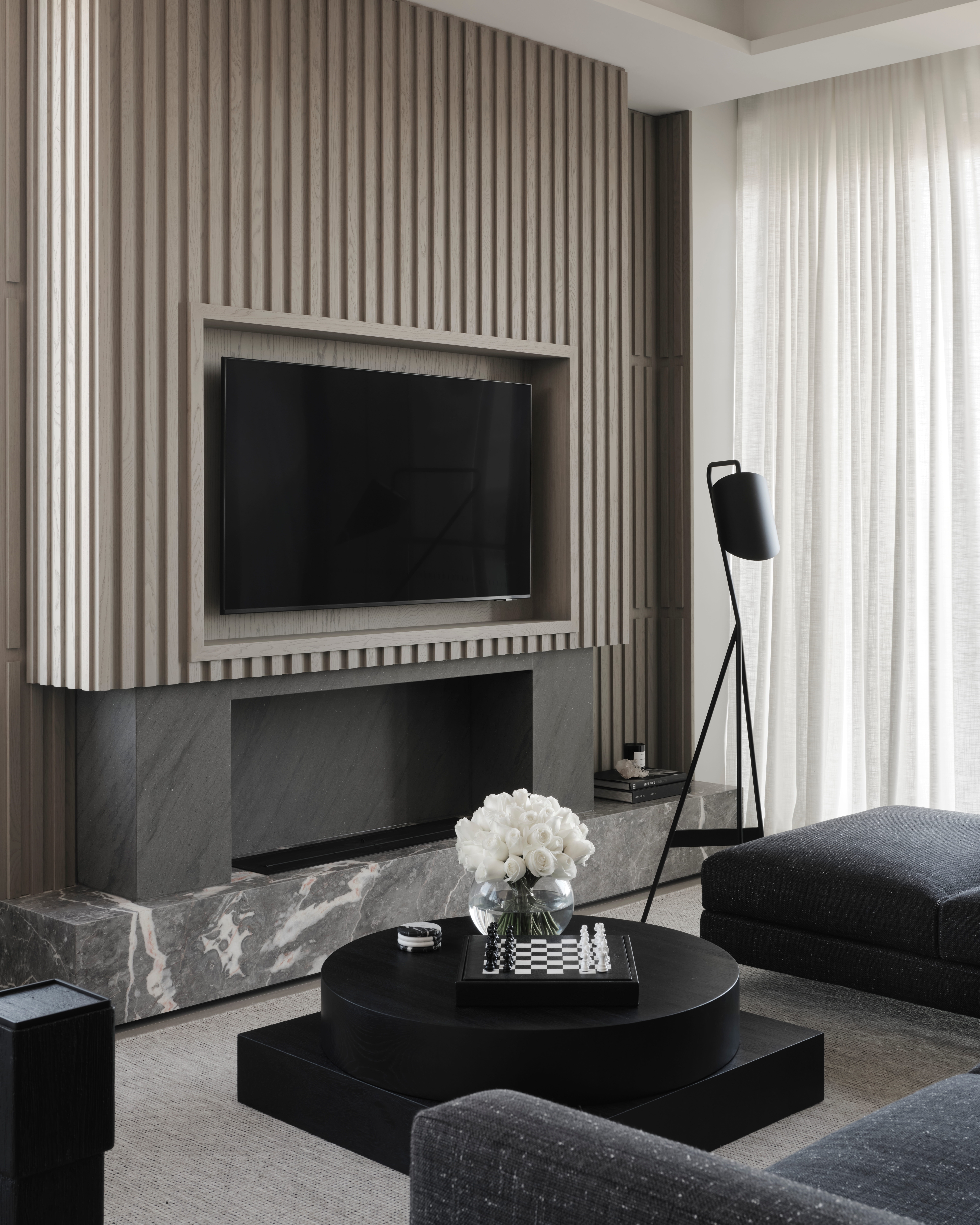 Freeman & Co living room with a timber-slat media wall, marble hearth and charcoal seating