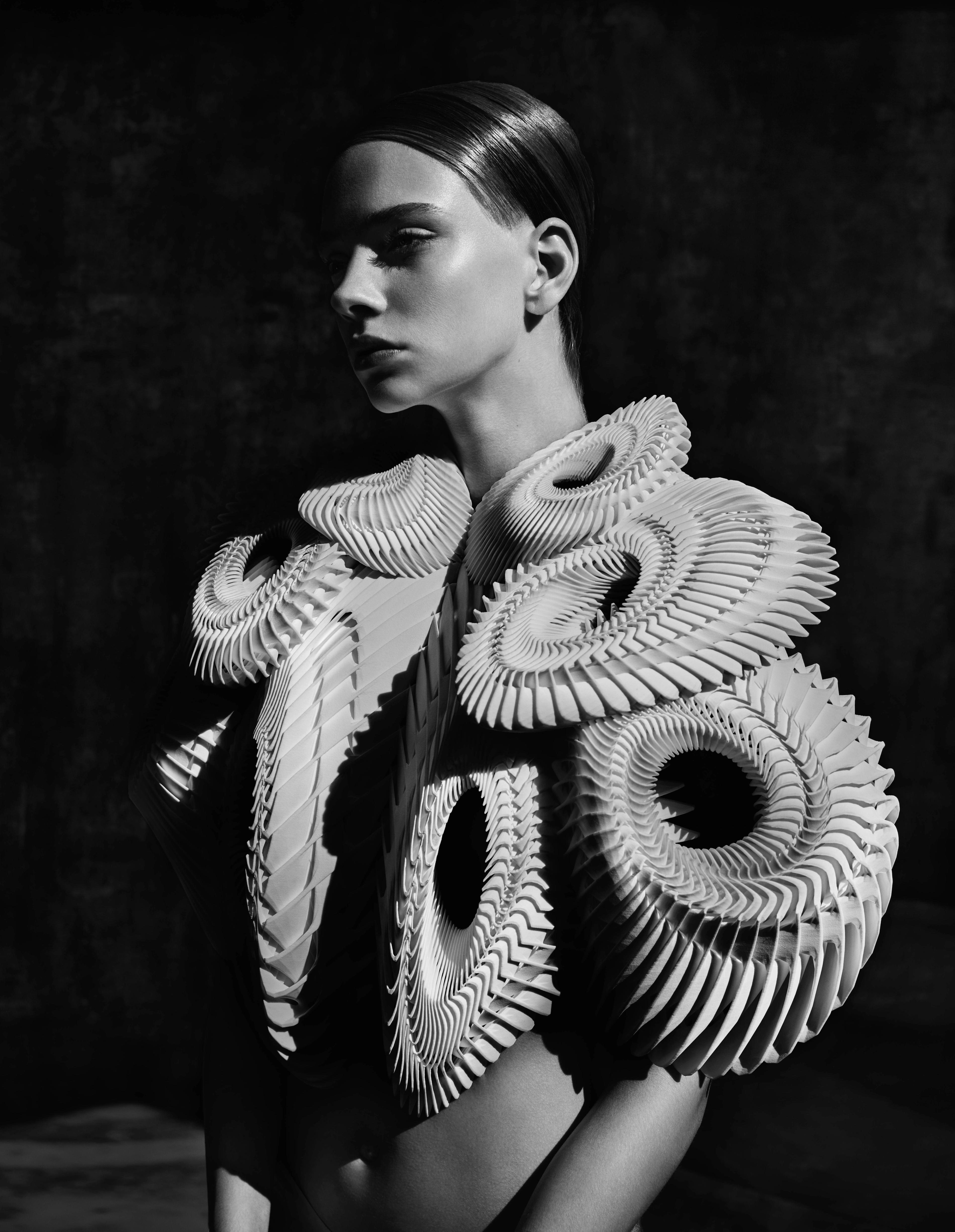 Coiled, pleated Iris van Herpen garment framing a model's shoulders in black and white