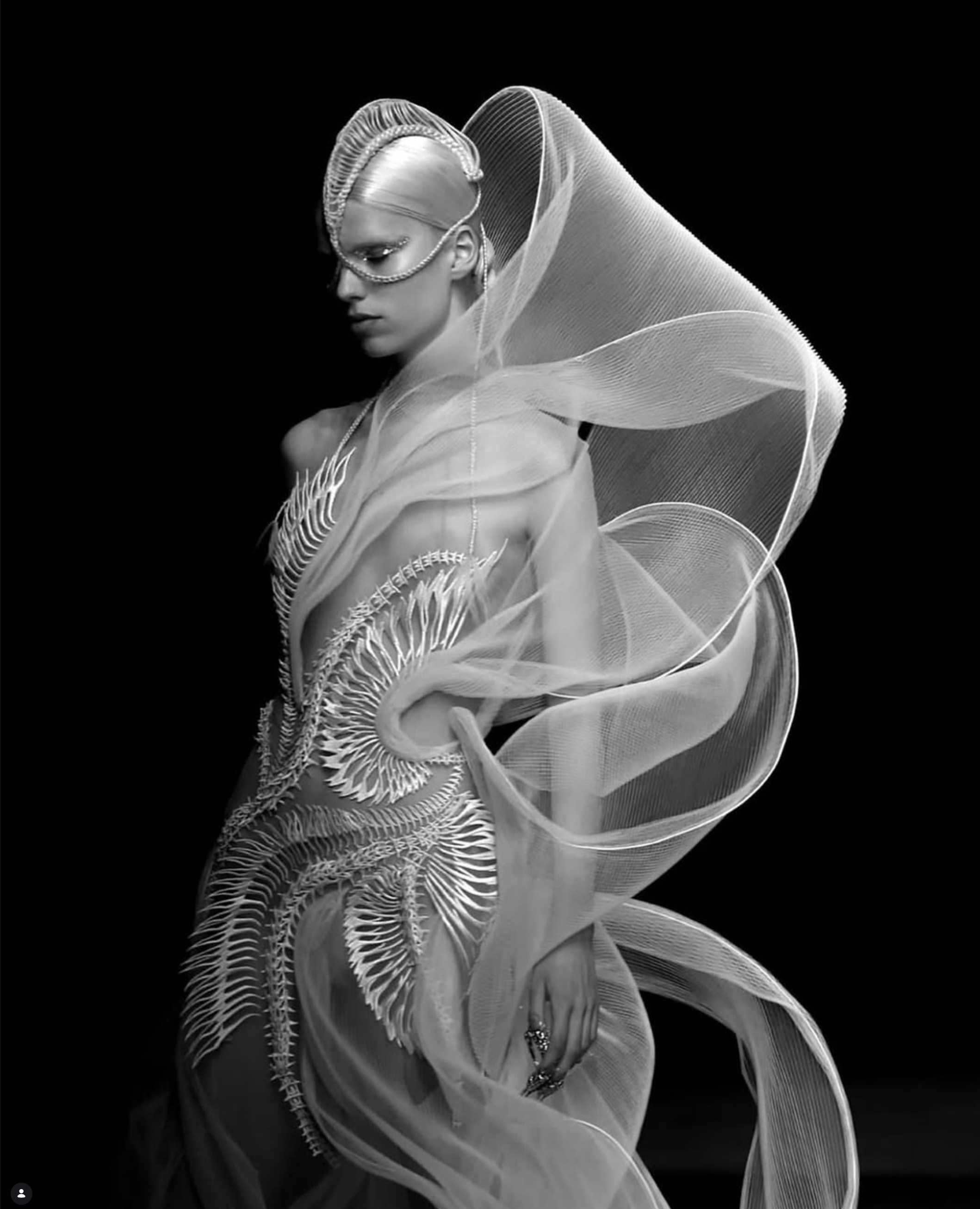 Metallic sculptural gown wrapped in swirling organza, worn by a model in monochrome