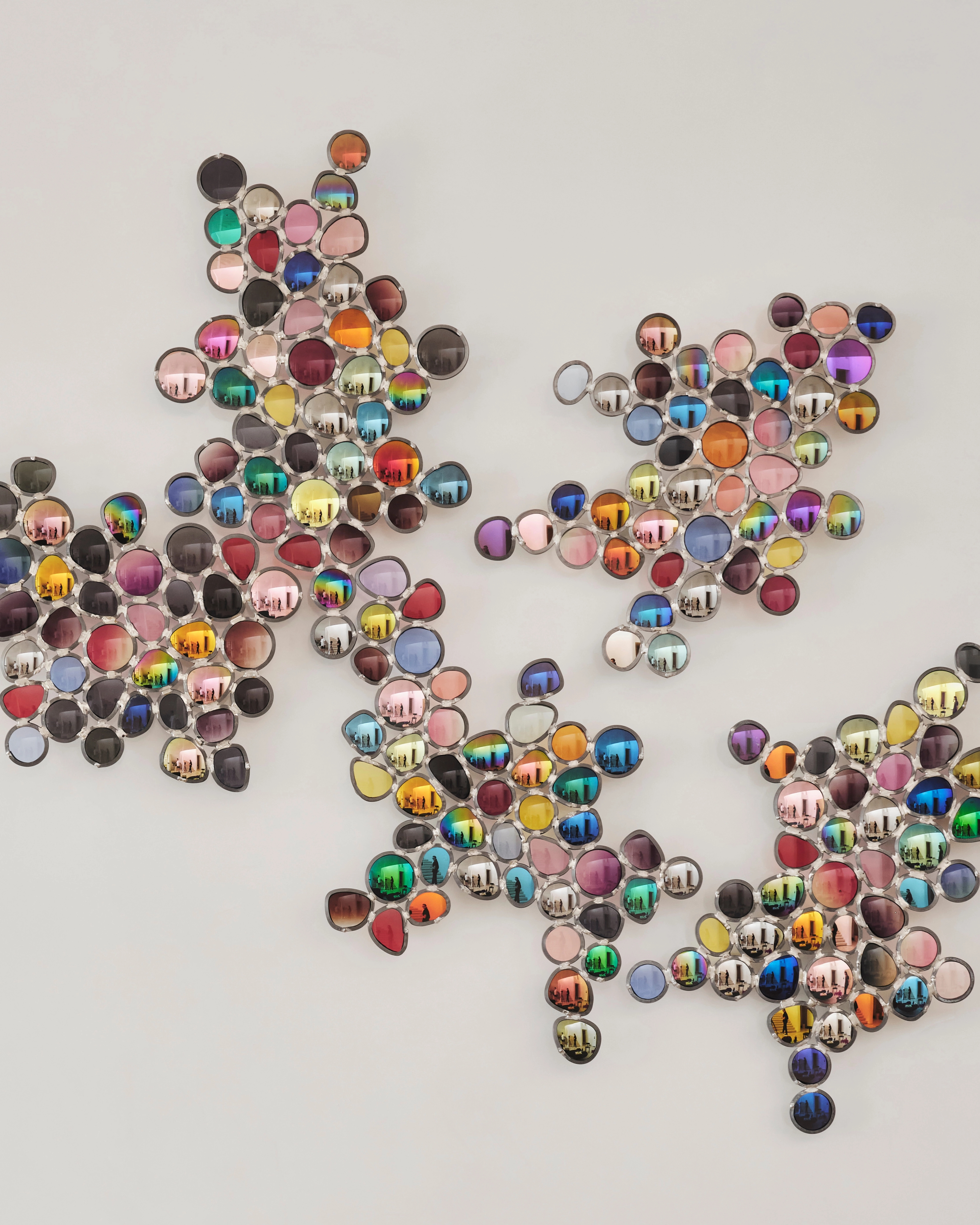 Wall installation of hundreds of jewel-toned glass discs scattered across white