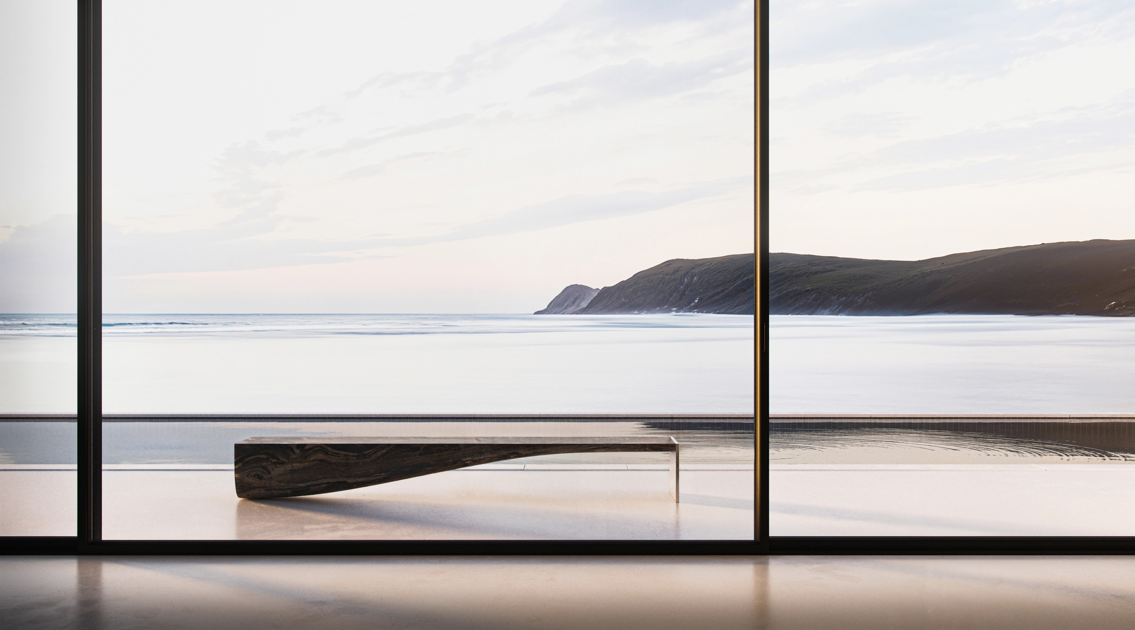 Floor-to-ceiling glazing framing a tranquil headland and still water above a low bench, South Coast