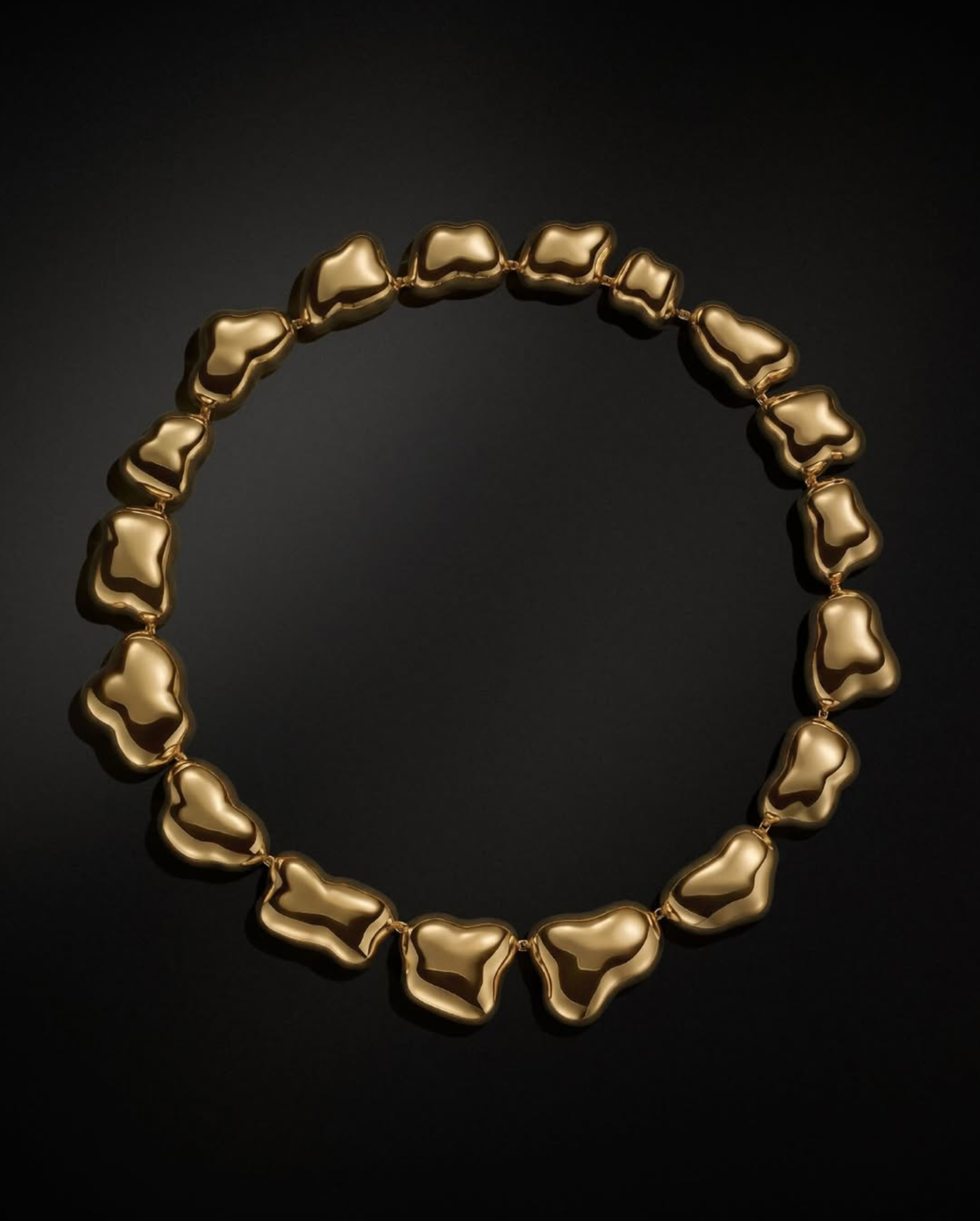 Chunky gold nugget-link necklace arranged in a circle on black