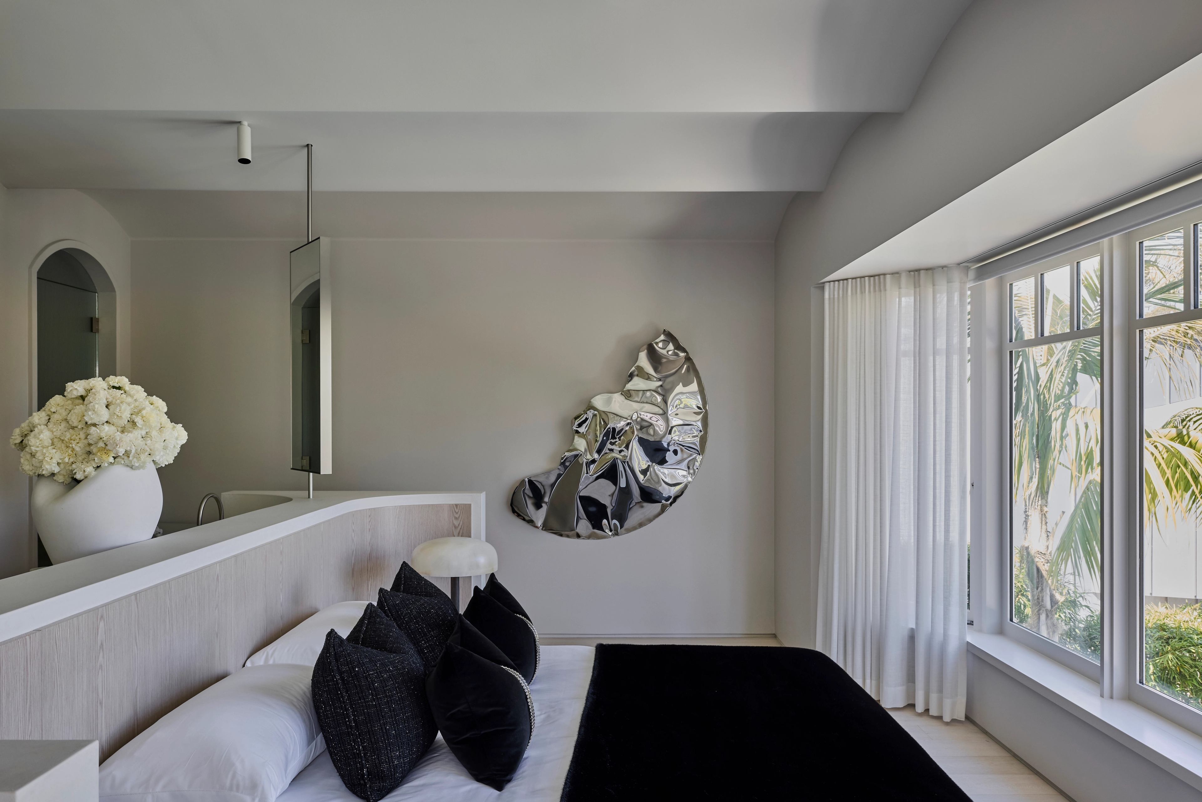 Main bedroom with sculptural mirror and garden outlook in Vaucluse