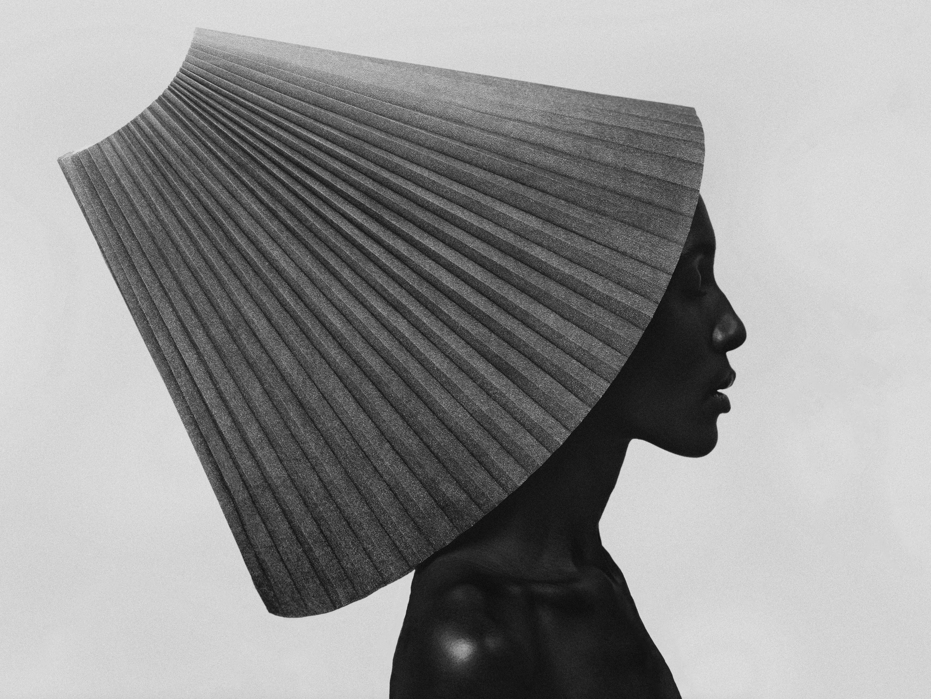 Profile portrait of a woman wearing a dramatic pleated fan collar, in black and white