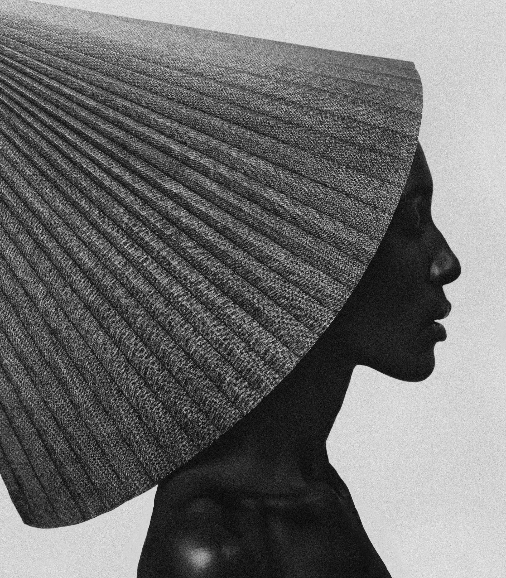 Profile portrait of a woman wearing a dramatic pleated fan collar, in black and white