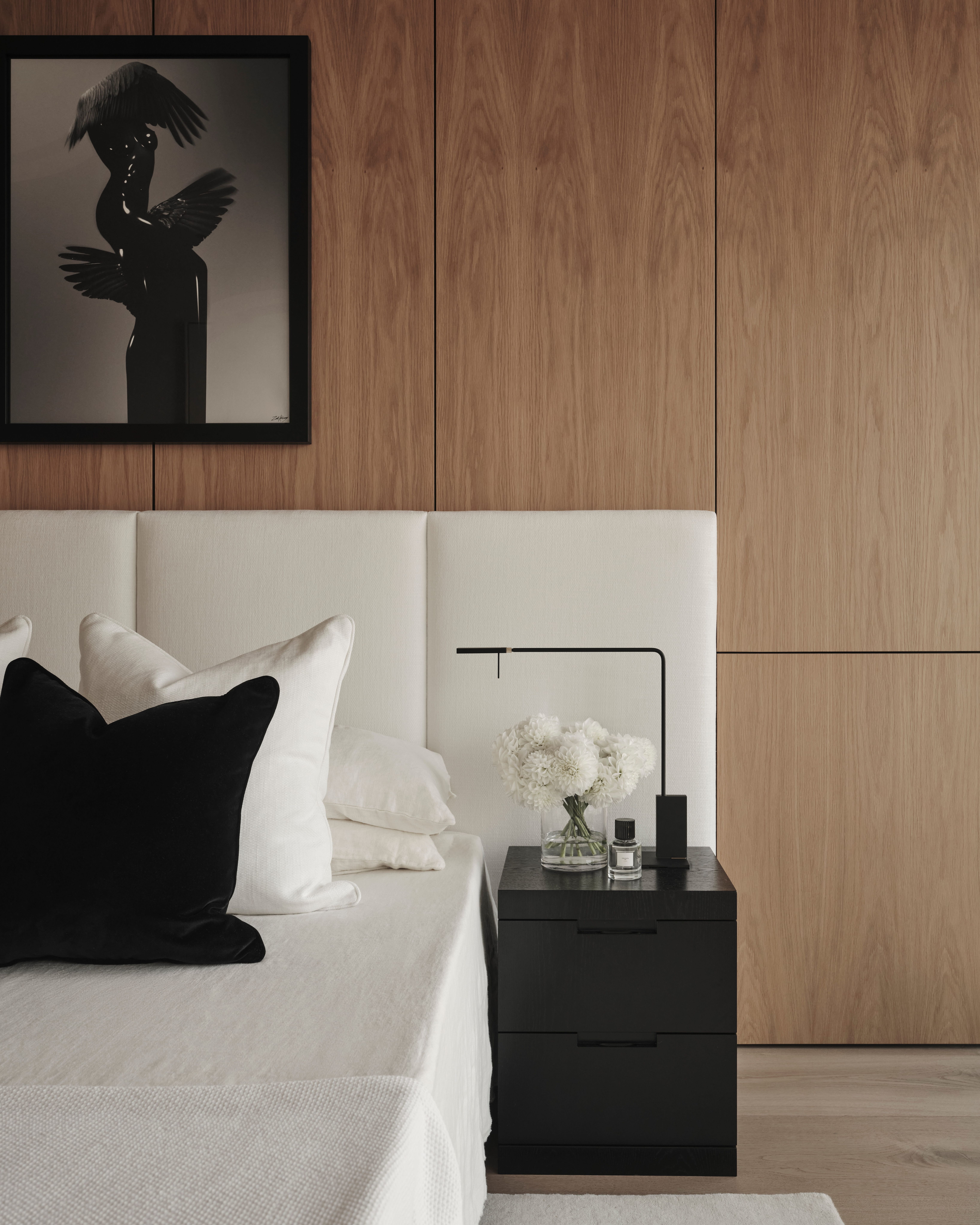 Sydney CBD bedroom with a timber-panelled wall, upholstered headboard and framed sculptural photograph