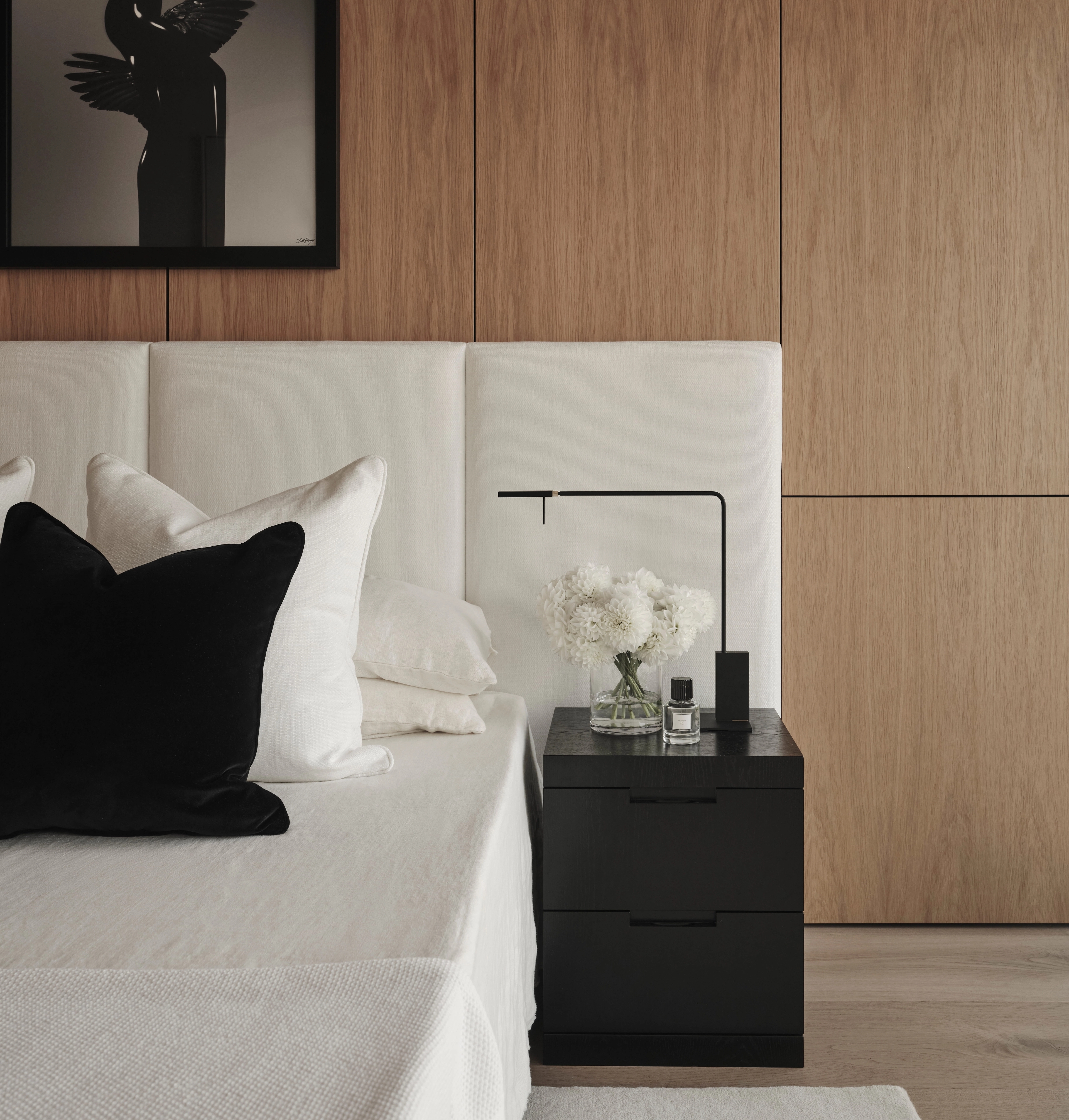 Sydney CBD bedroom with a timber-panelled wall, upholstered headboard and framed sculptural photograph