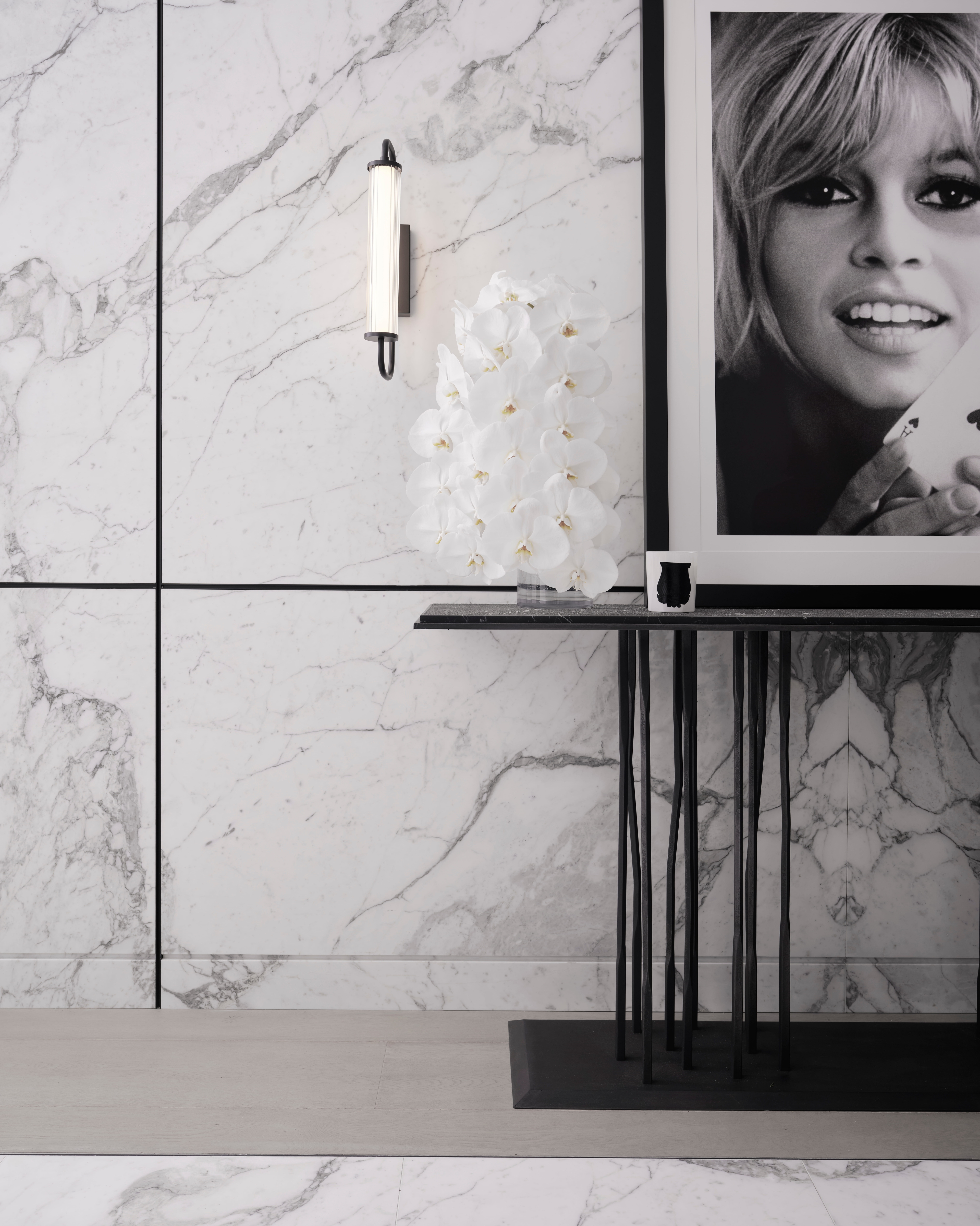 Slender black console beneath a framed Brigitte Bardot portrait against bookmatched marble, The Rocks