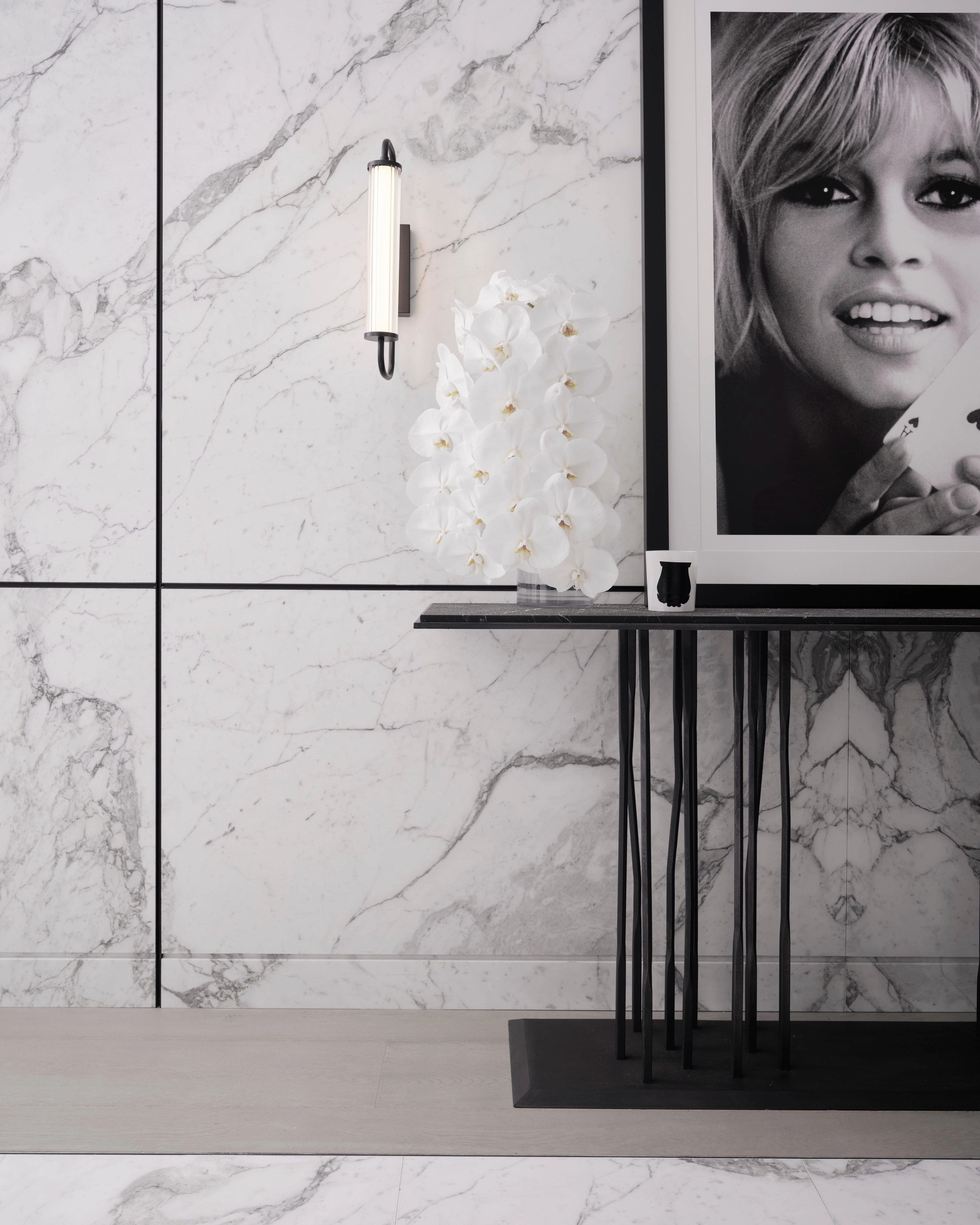 Slender black console beneath a framed Brigitte Bardot portrait against bookmatched marble, The Rocks