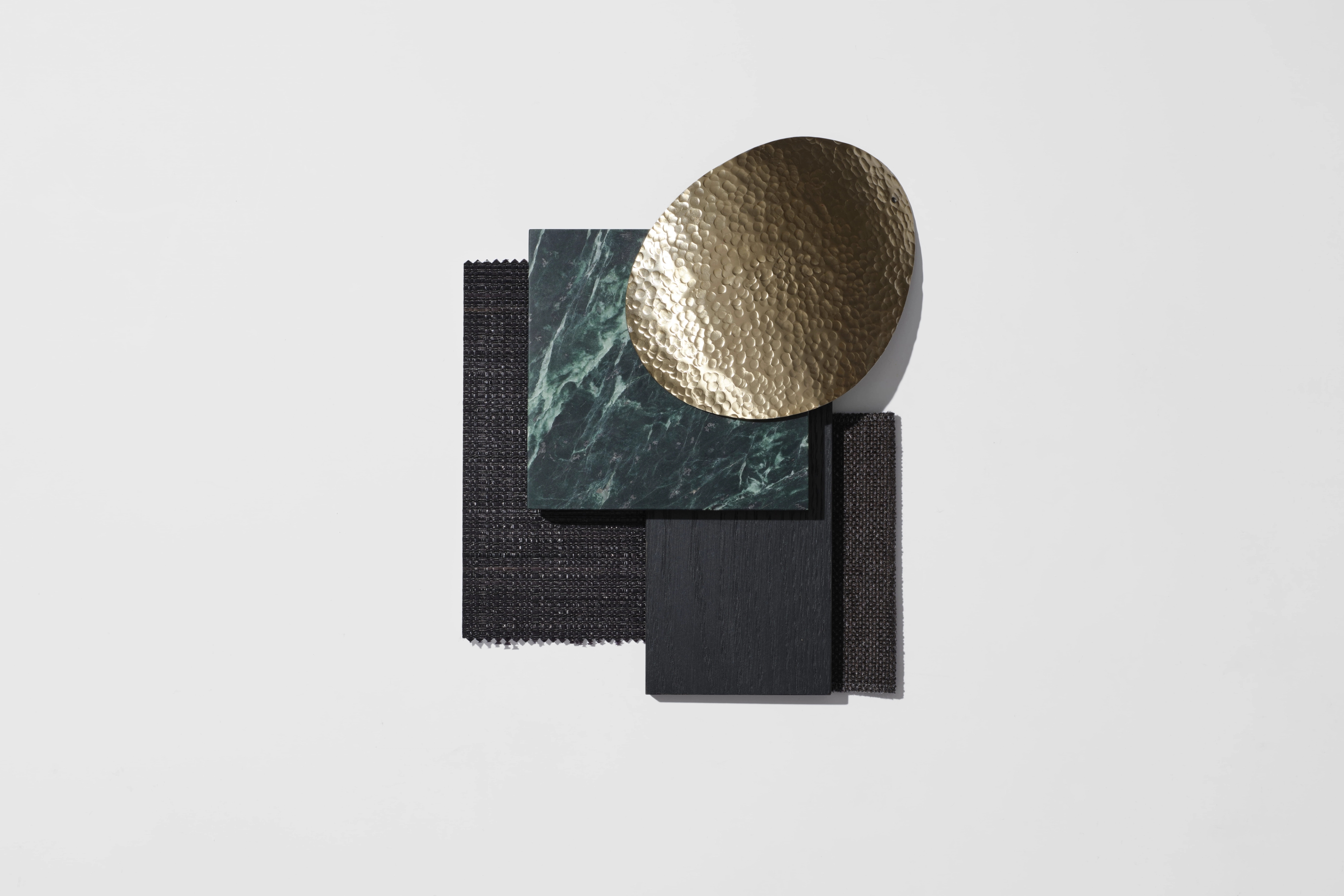 Materials palette pairing a hammered gold disc with green marble and dark textured samples