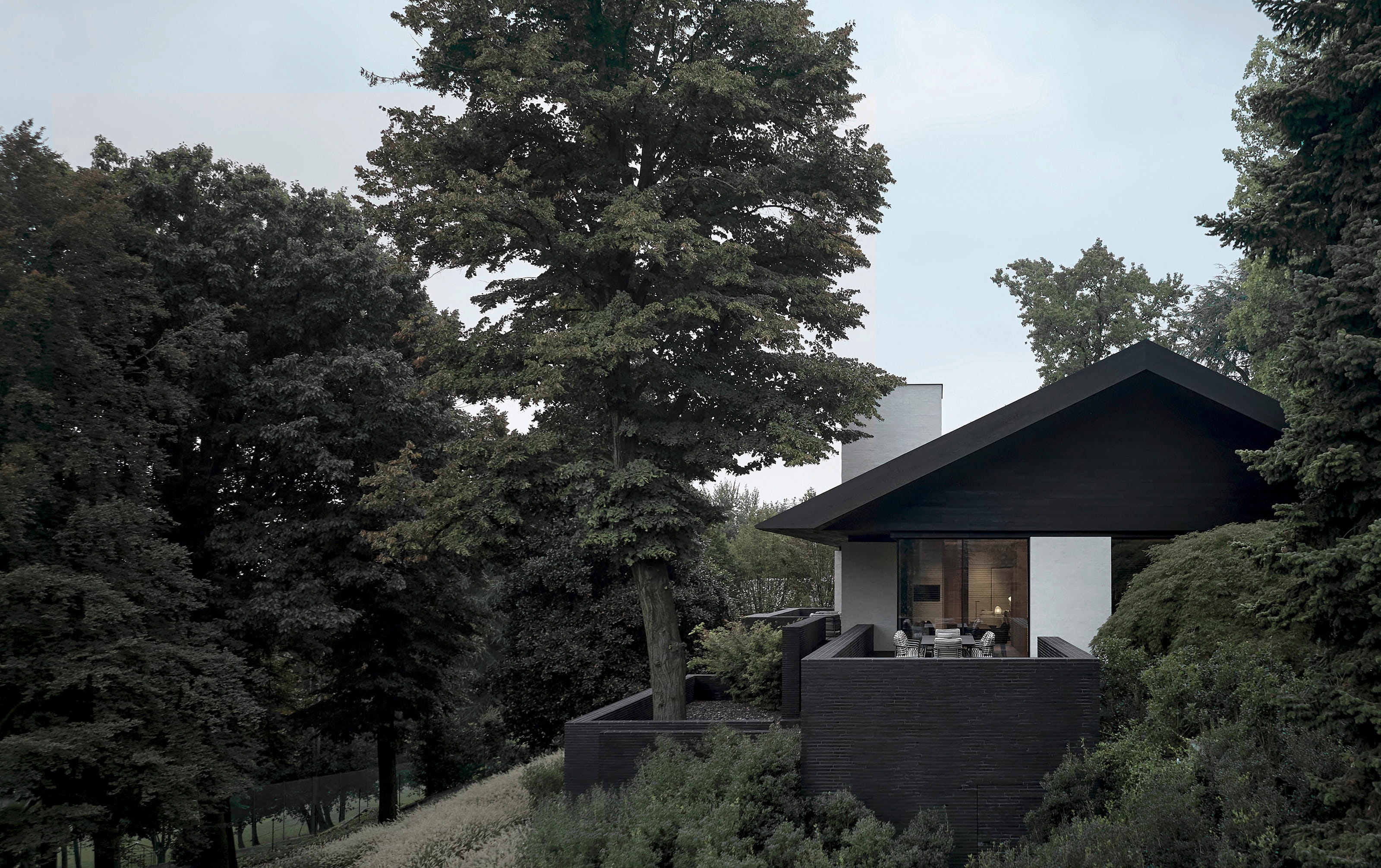 Vincent Van Duysen's dark timber pavilion nestled among mature trees on a hillside