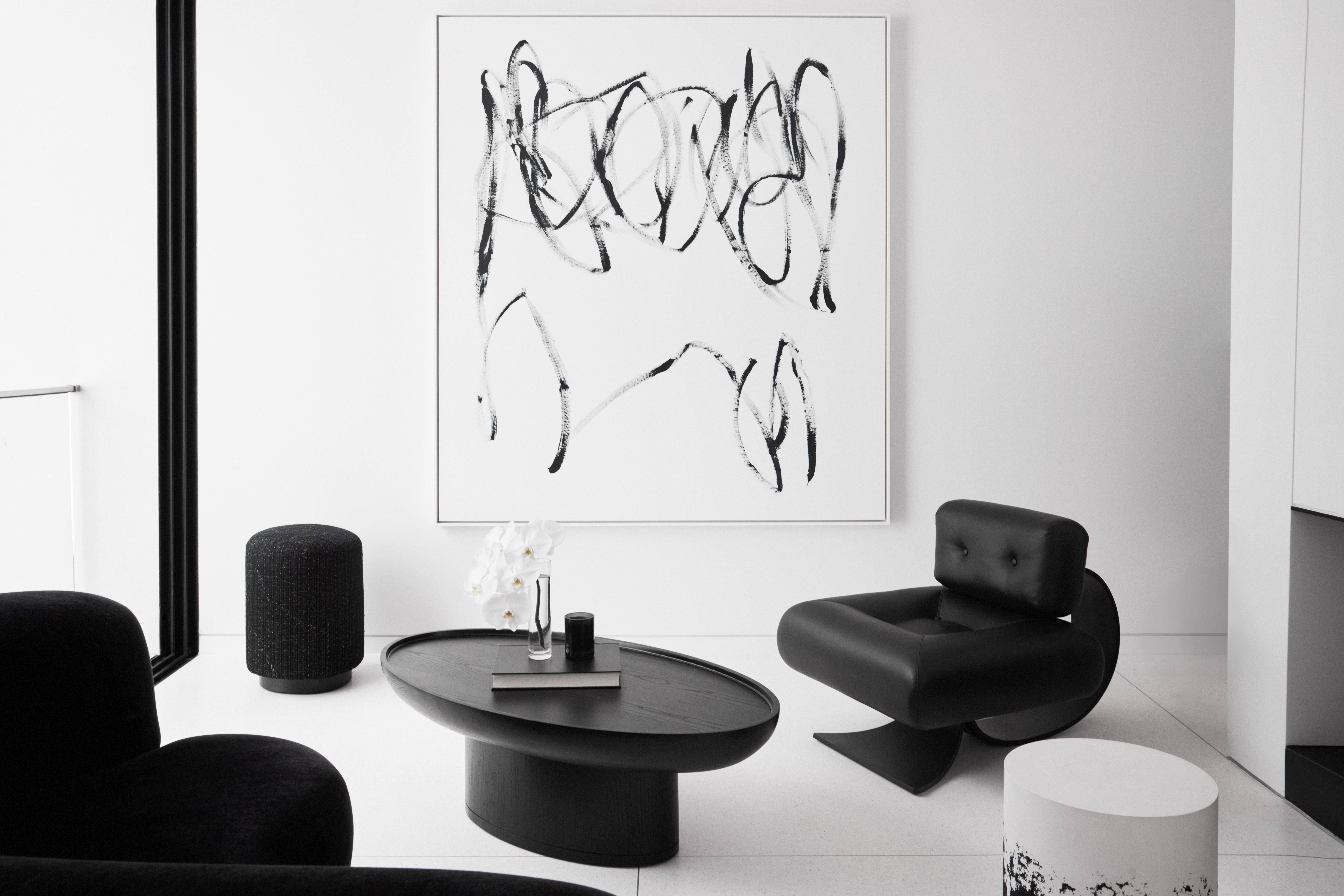 Restrained sitting room with a gestural line painting above sculptural black-and-white seating