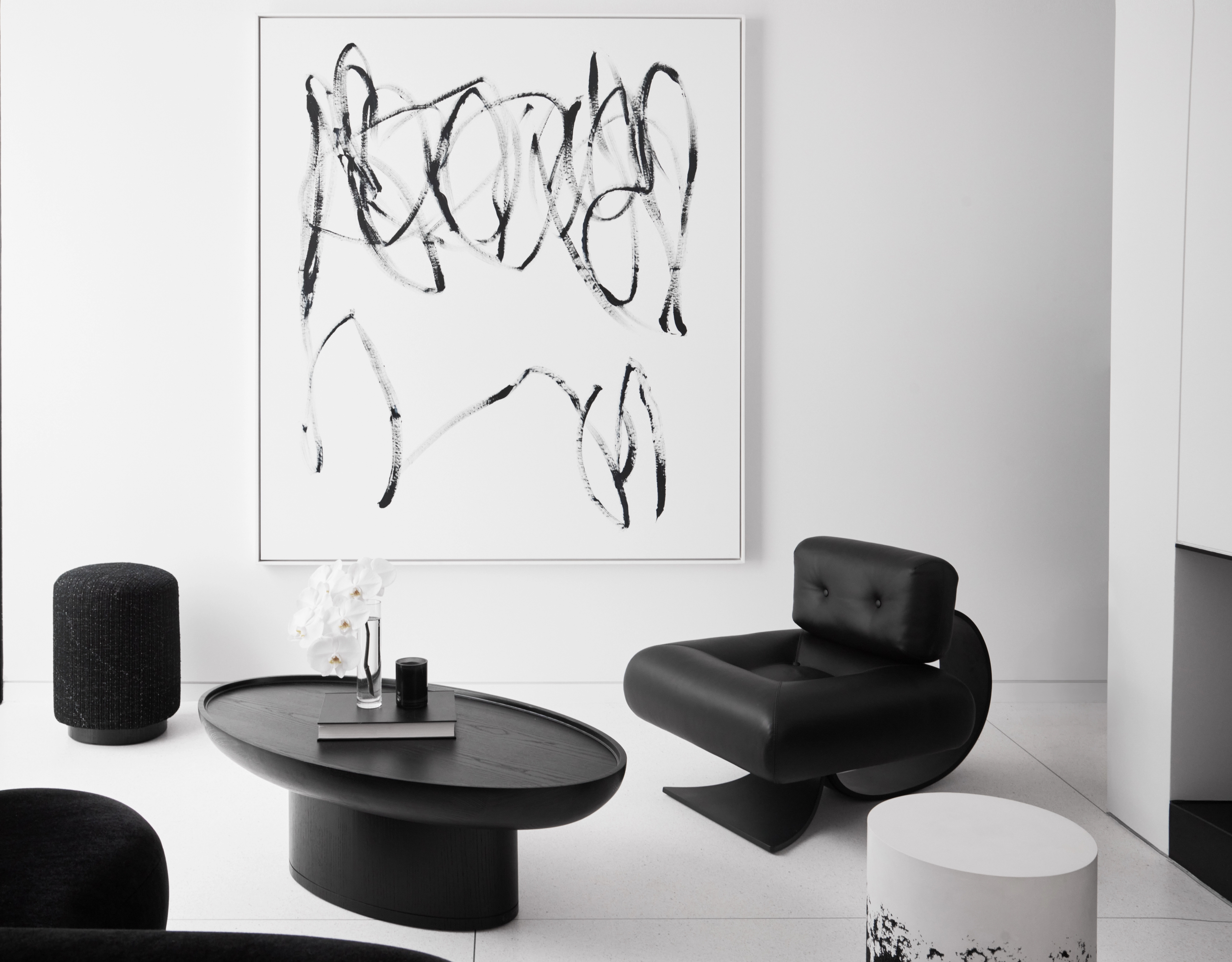 Restrained sitting room with a gestural line painting above sculptural black-and-white seating