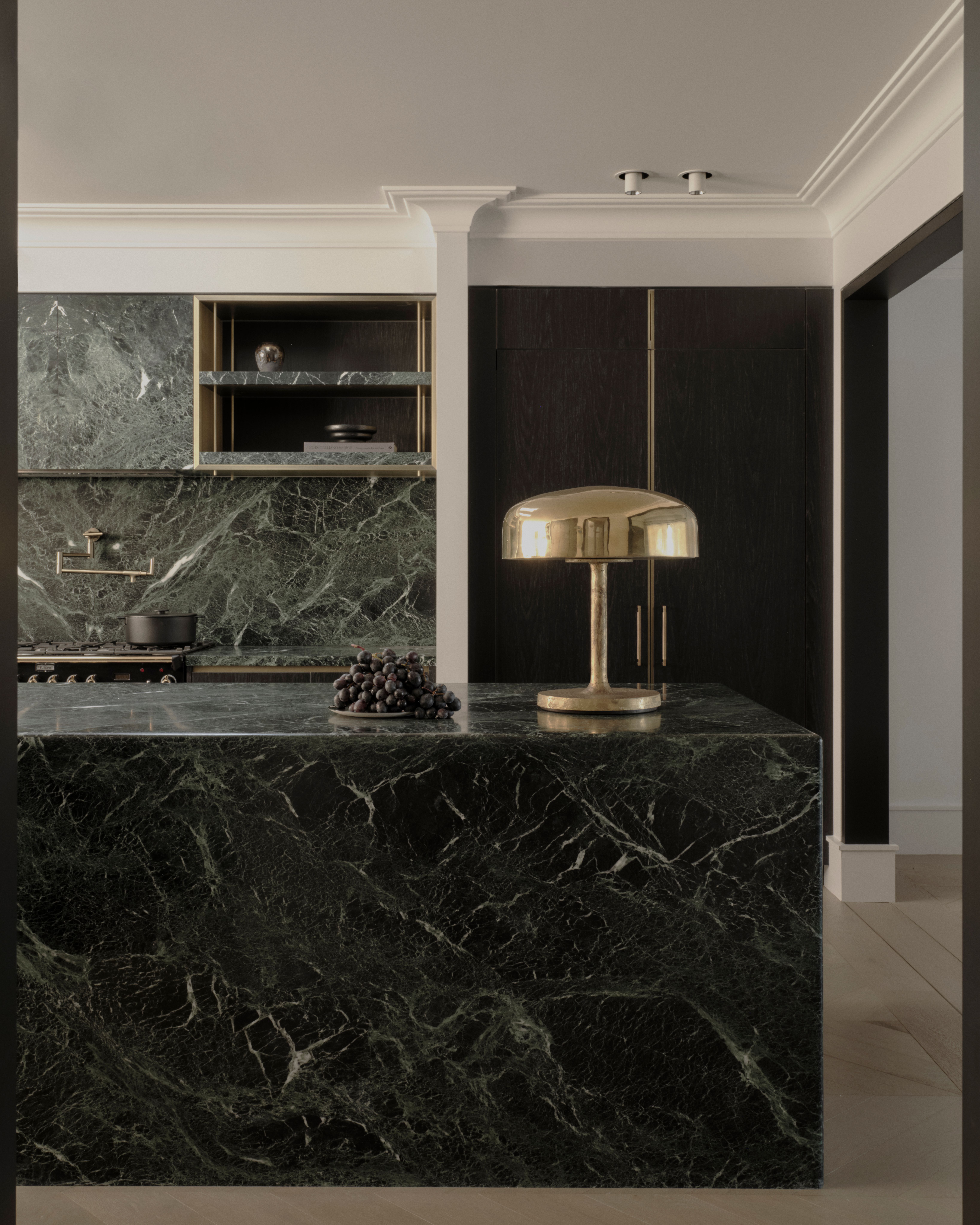 Moody Vaucluse kitchen with a green-marble island and brass mushroom lamp