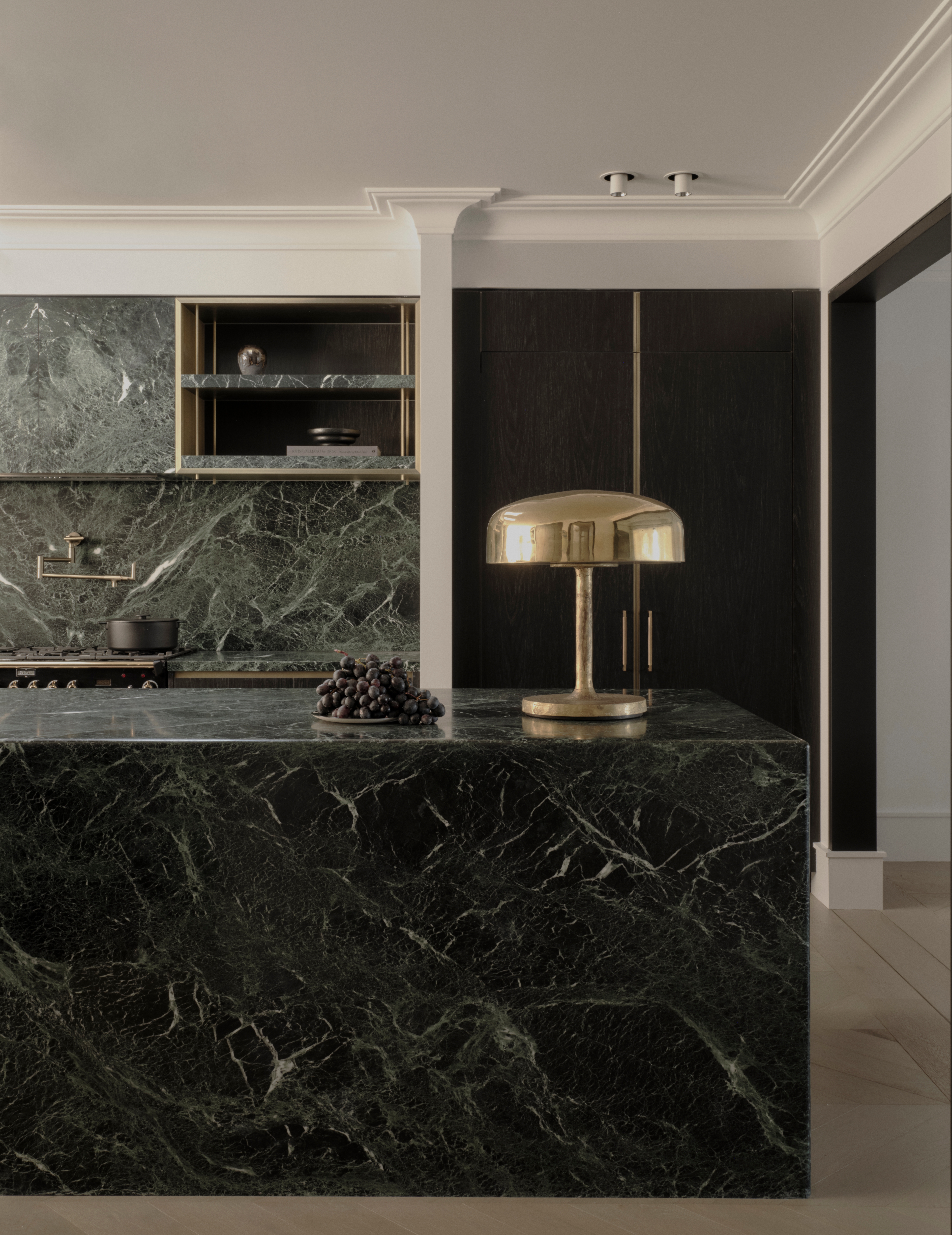 Moody Vaucluse kitchen with a green-marble island and brass mushroom lamp