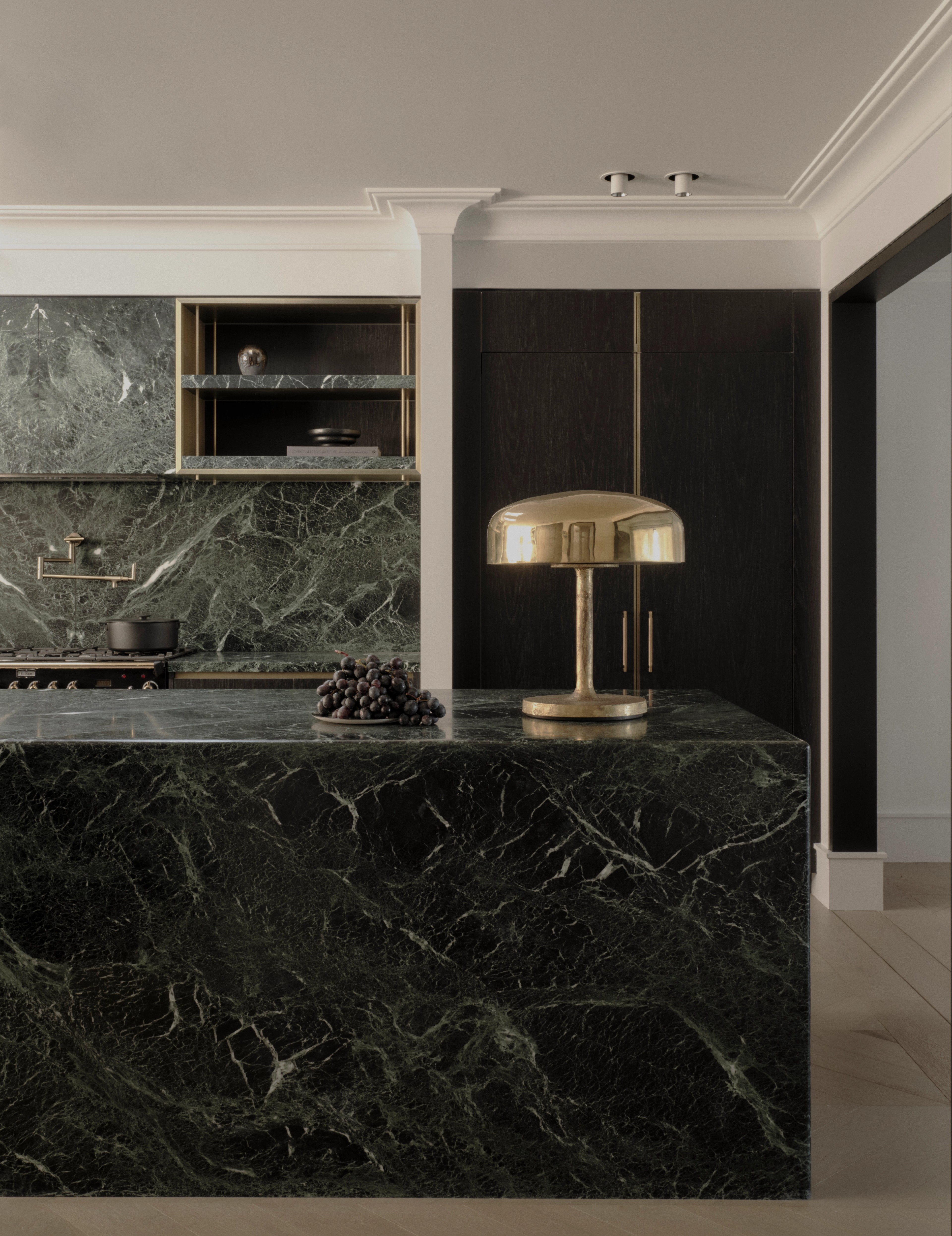 Moody Vaucluse kitchen with a green-marble island and brass mushroom lamp