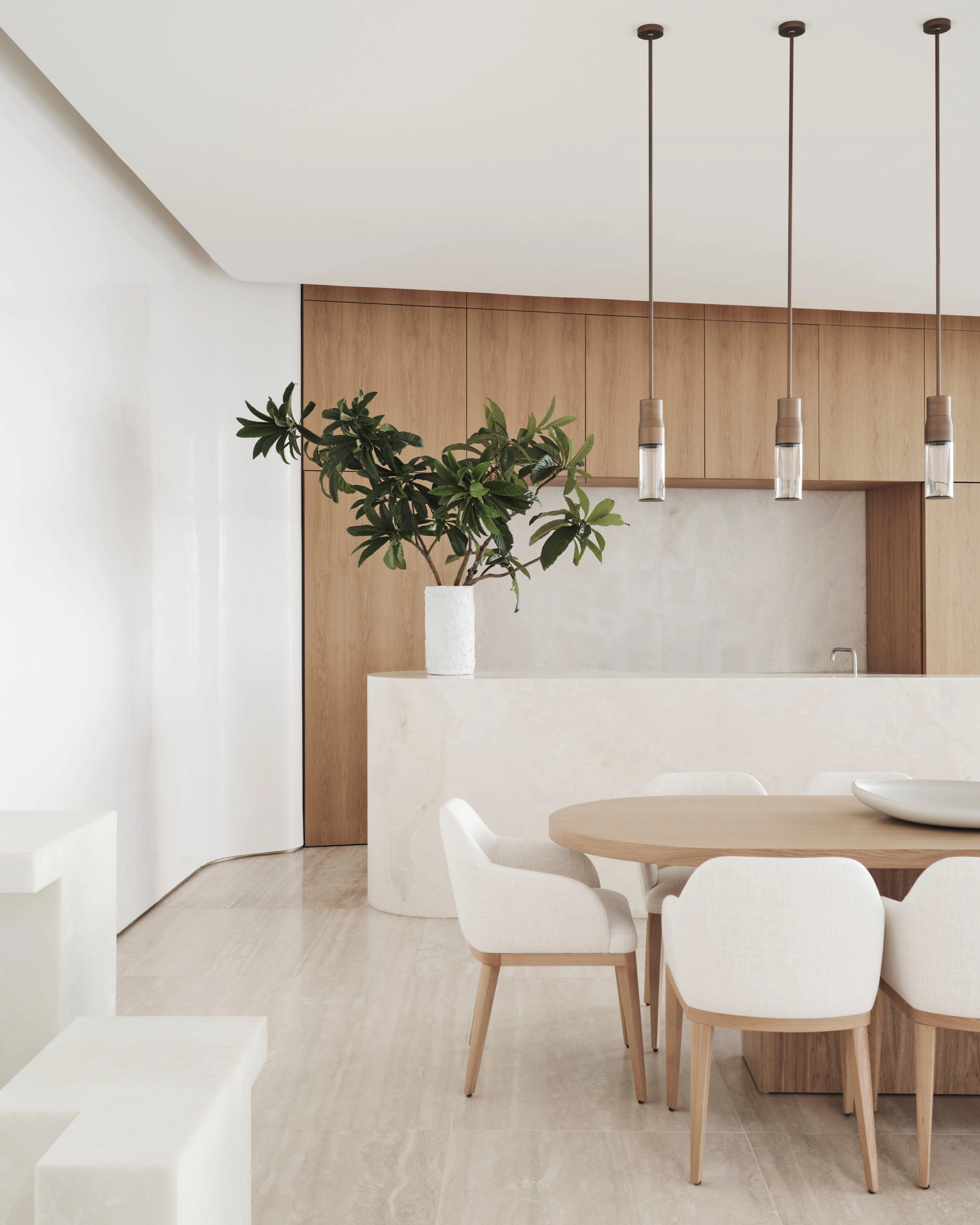 Pale-toned Sydney CBD dining nook with a round timber table and clustered glass pendants
