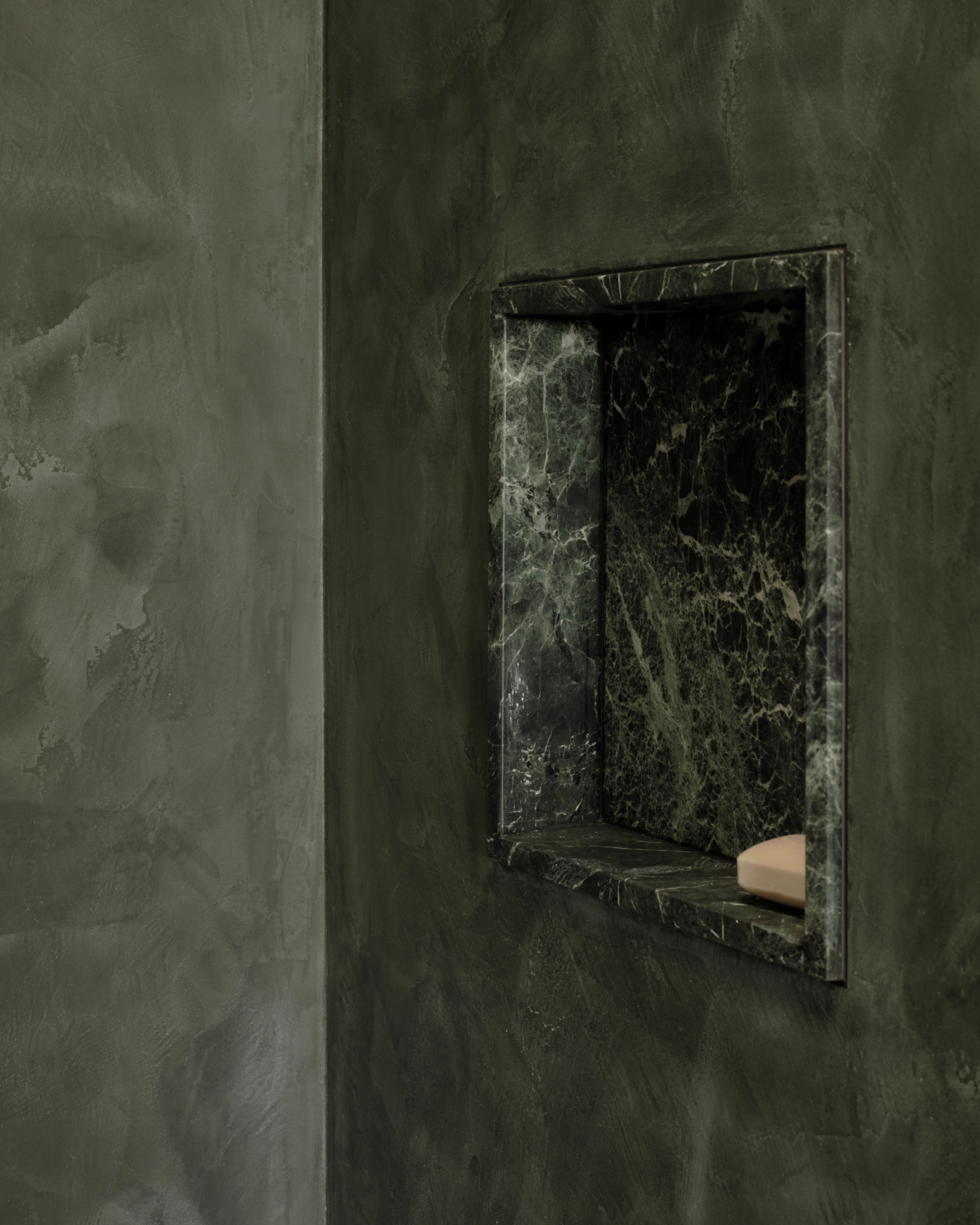 Vaucluse wall of deep-green polished plaster framing a marble-lined recessed niche