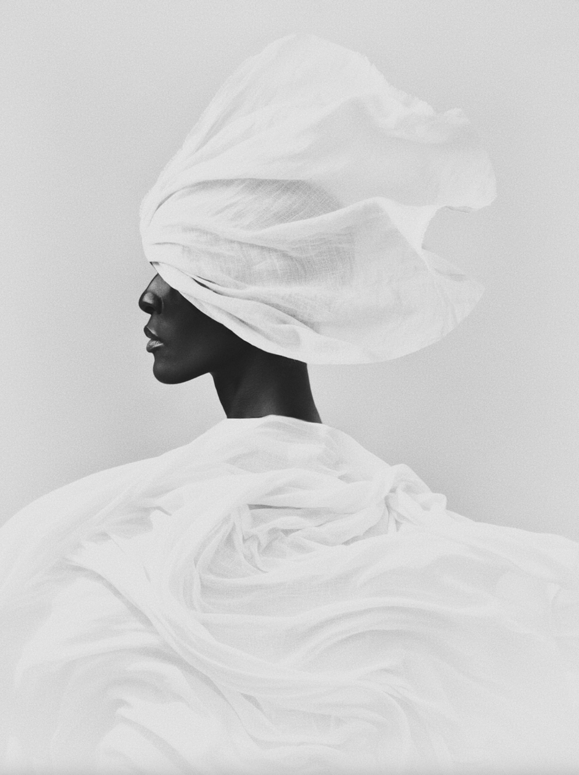 Black-and-white profile of a woman in a sculptural white turban by photographer Bastiaan Woudt