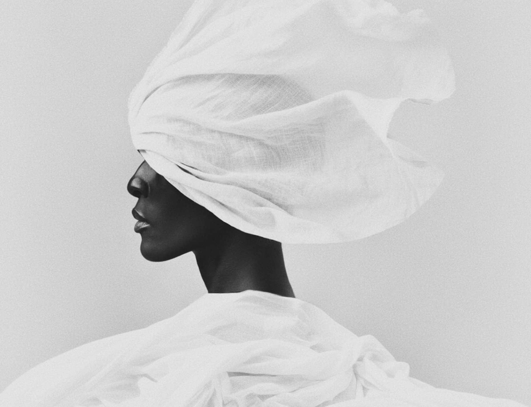 Black-and-white profile of a woman in a sculptural white turban by photographer Bastiaan Woudt