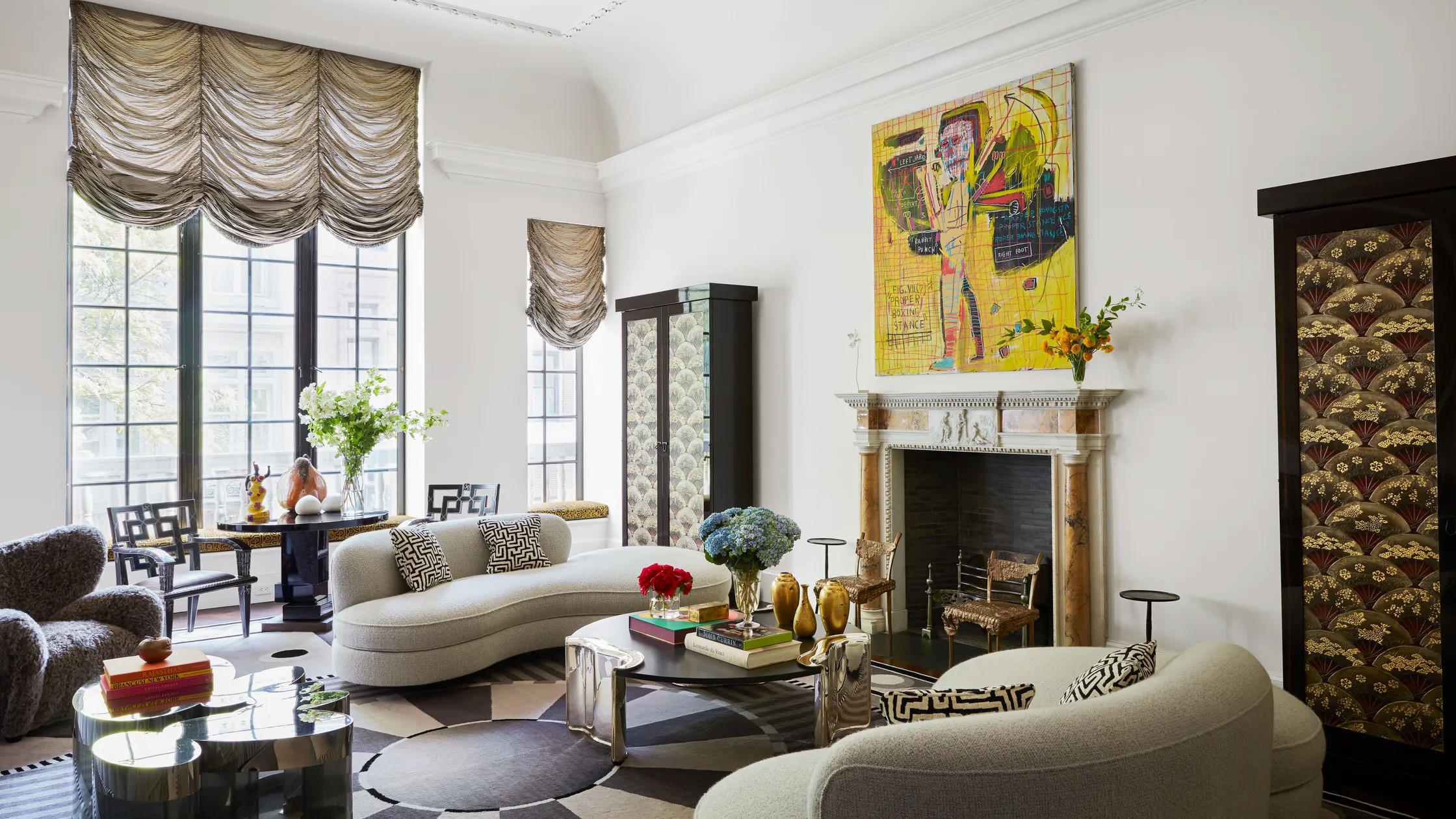 Eclectic sitting room with a colourful painting above the mantel, curved sofas and patterned screen