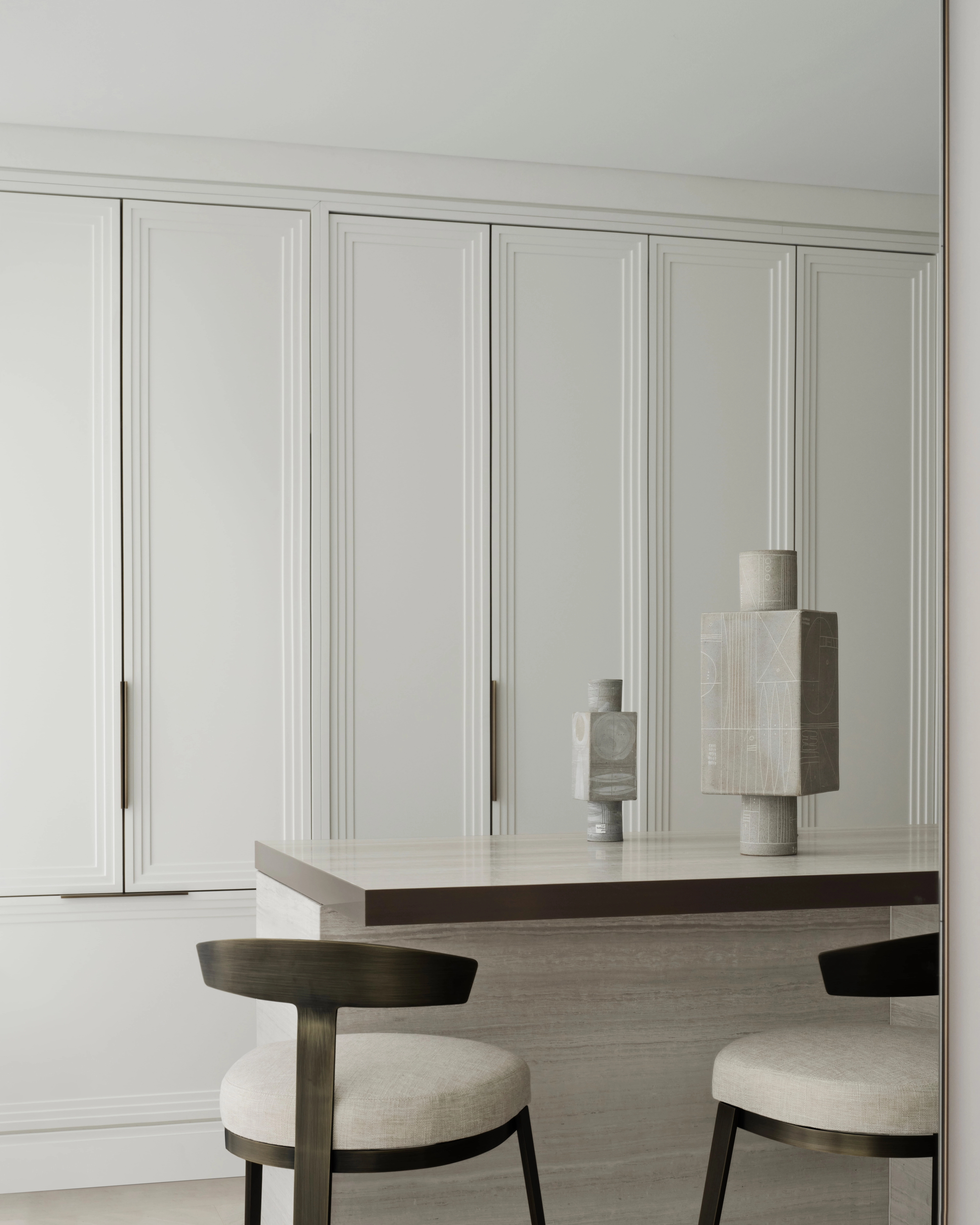 Breakfast bar with upholstered stools and pale joinery styled with ceramic vessels, Elizabeth Bay