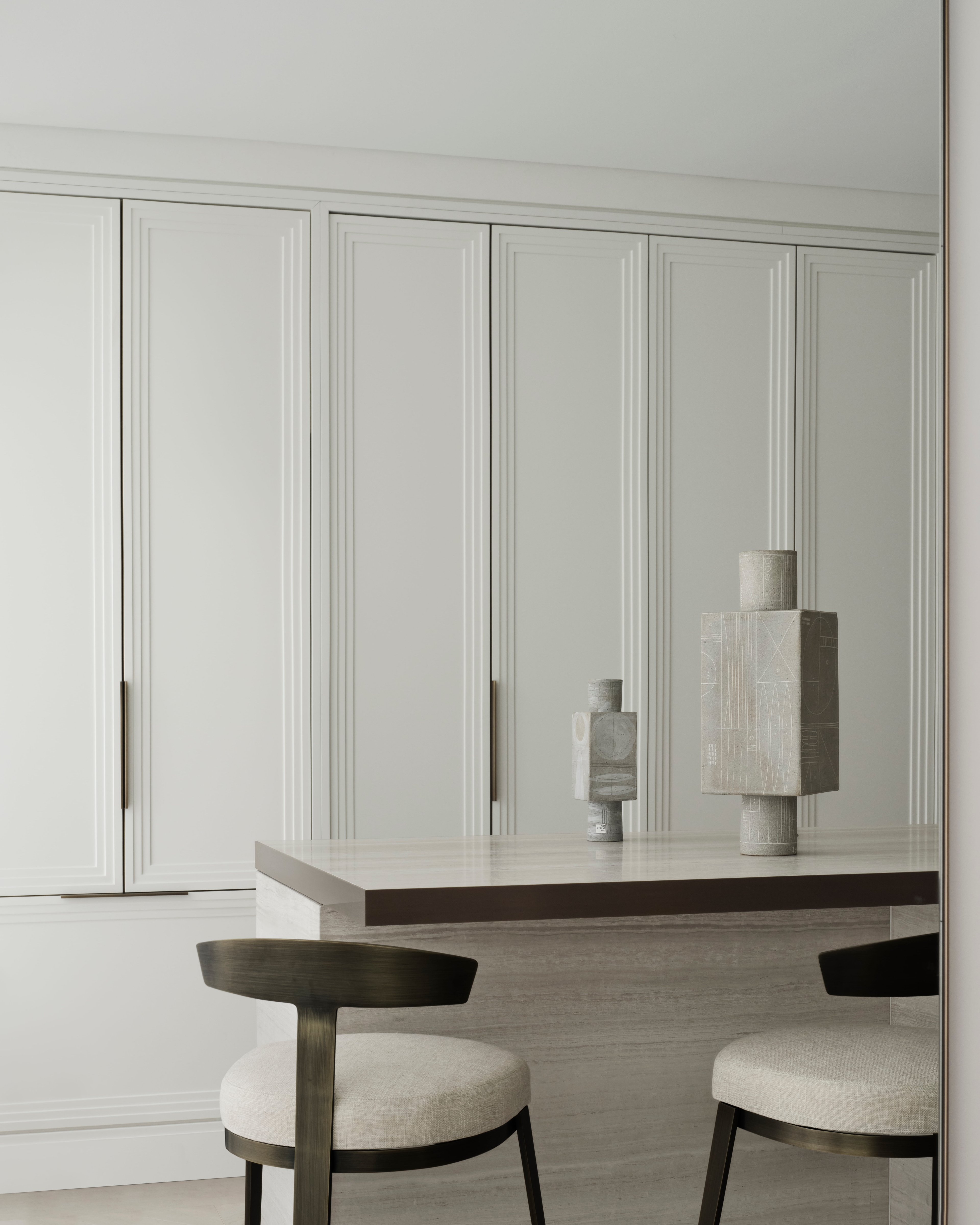 Breakfast bar with upholstered stools and pale joinery styled with ceramic vessels, Elizabeth Bay