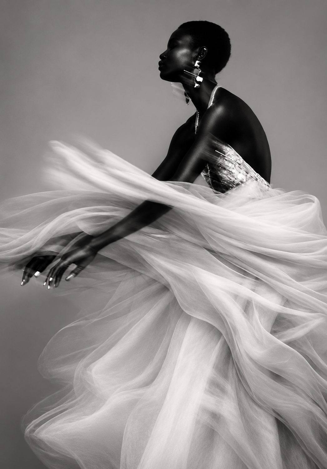 Sweeping black-and-white study of a woman swathed in billowing tulle, one arm extended