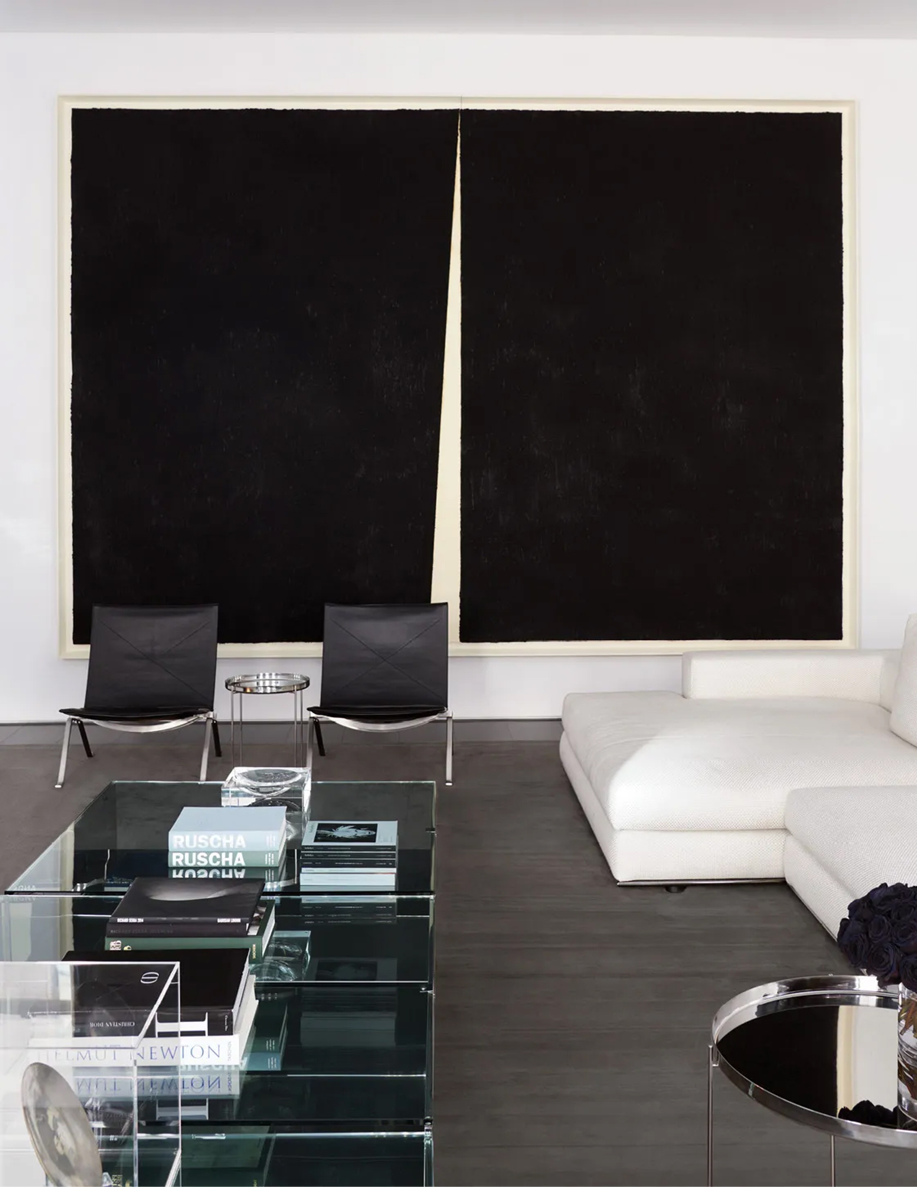 Pared-back room in Vera Wang's home with a dark diptych, white sofa and glass table