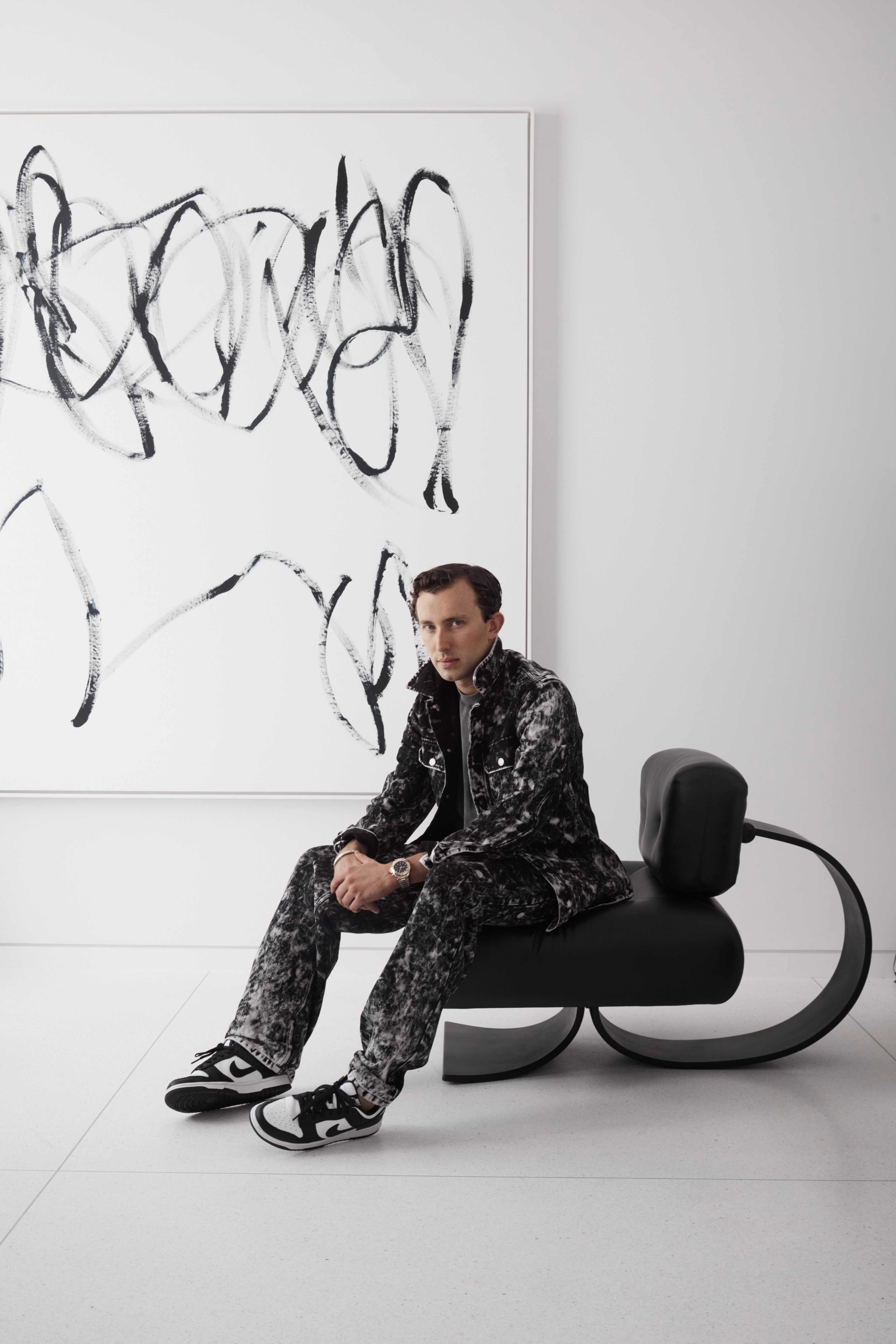 Freeman & Co founder Jack Freeman seated on a sculptural chair beside an abstract artwork