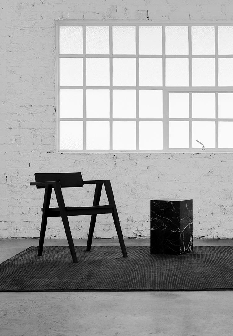 Spare loft with a black chair and cube beneath a gridded window