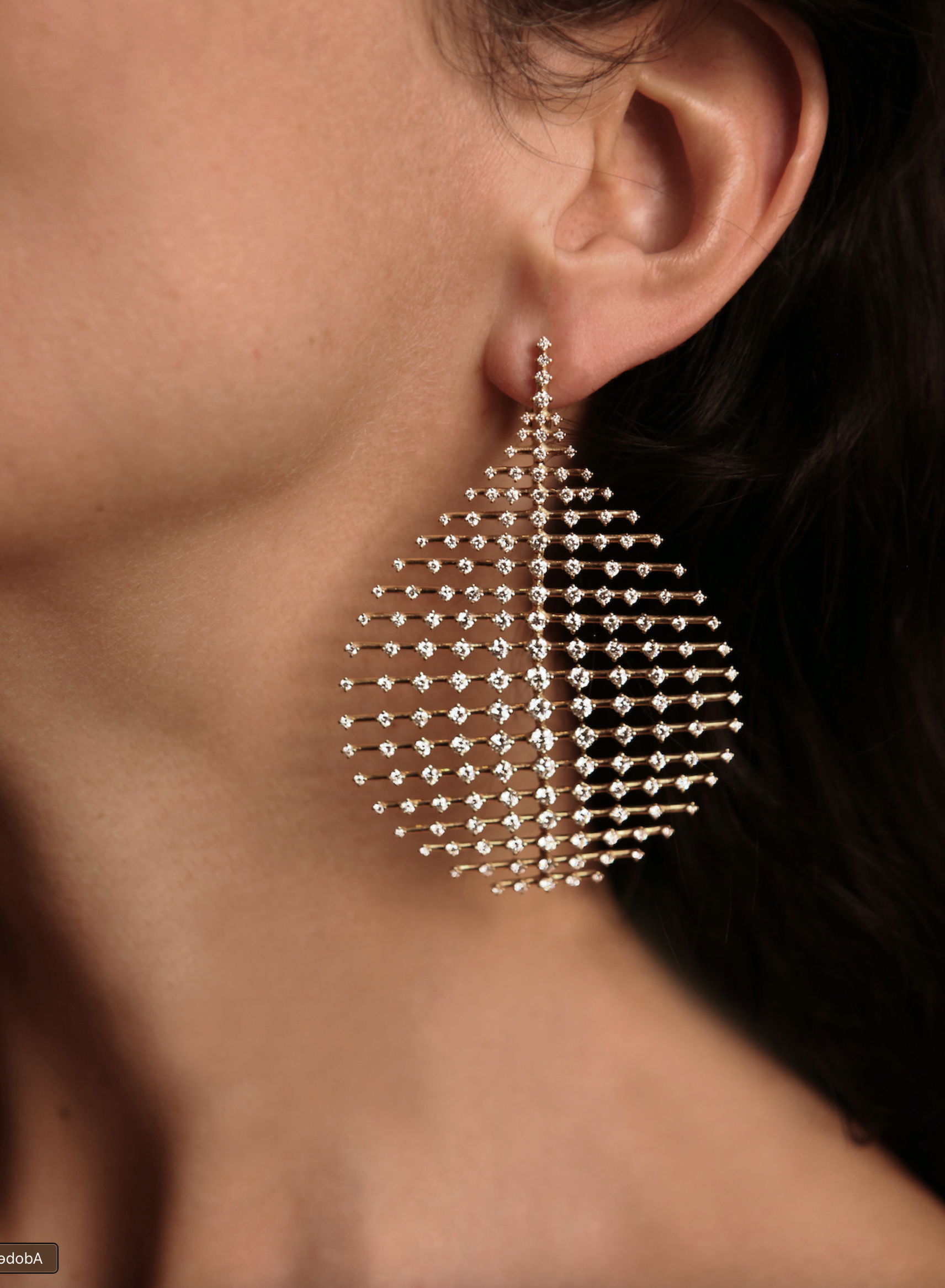 Close-up of a teardrop earring paved with crystals against a model's neck