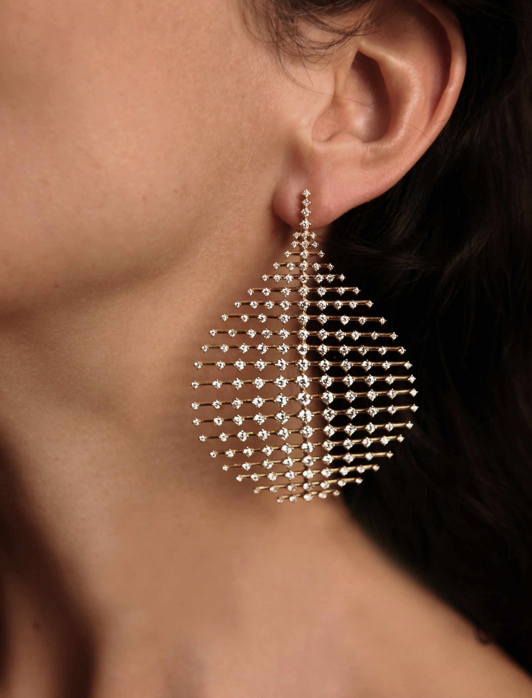 Close-up of a teardrop earring paved with crystals against a model's neck