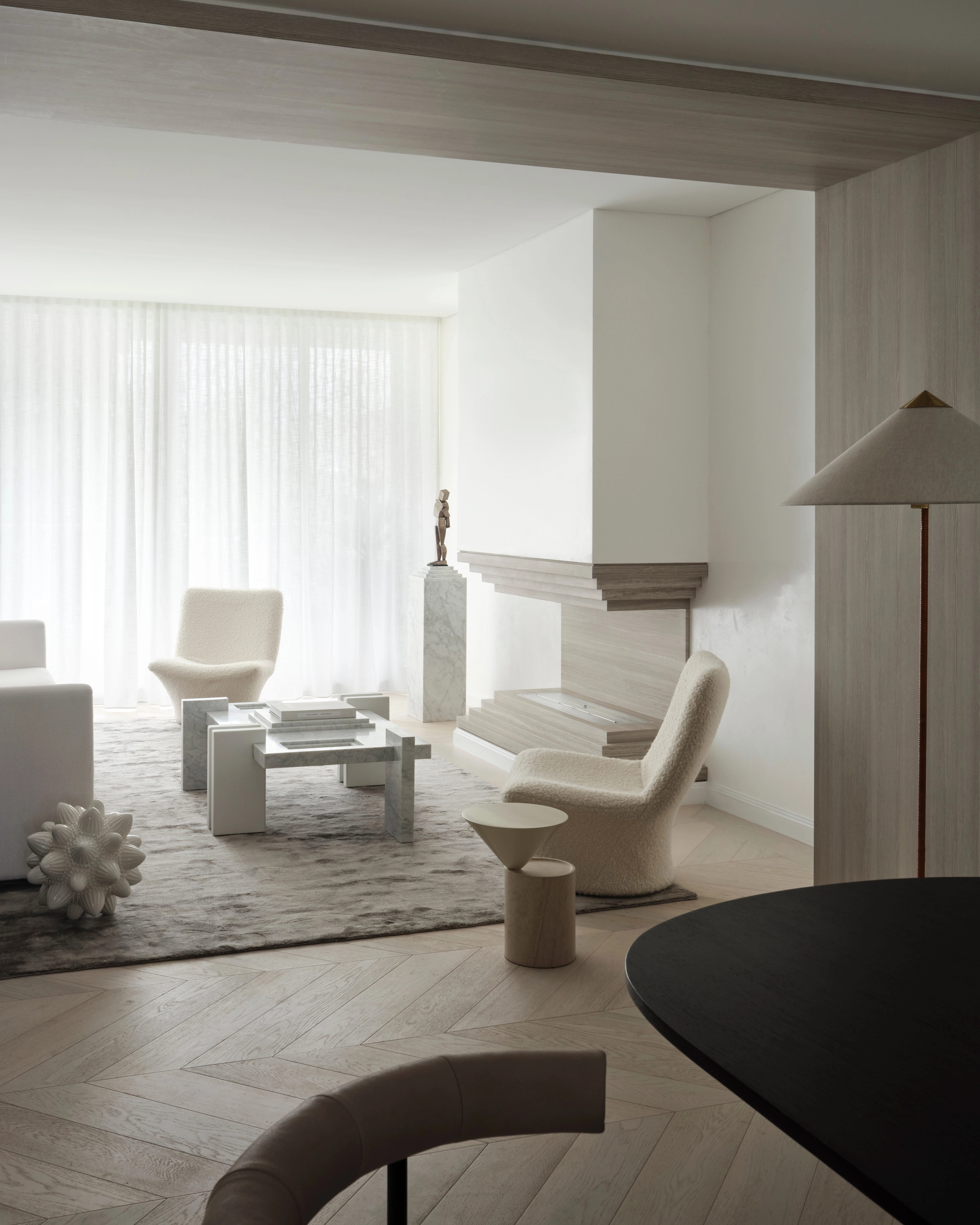 Sun-filled sitting room with sculptural armchairs and herringbone floors by Vincent Van Duysen