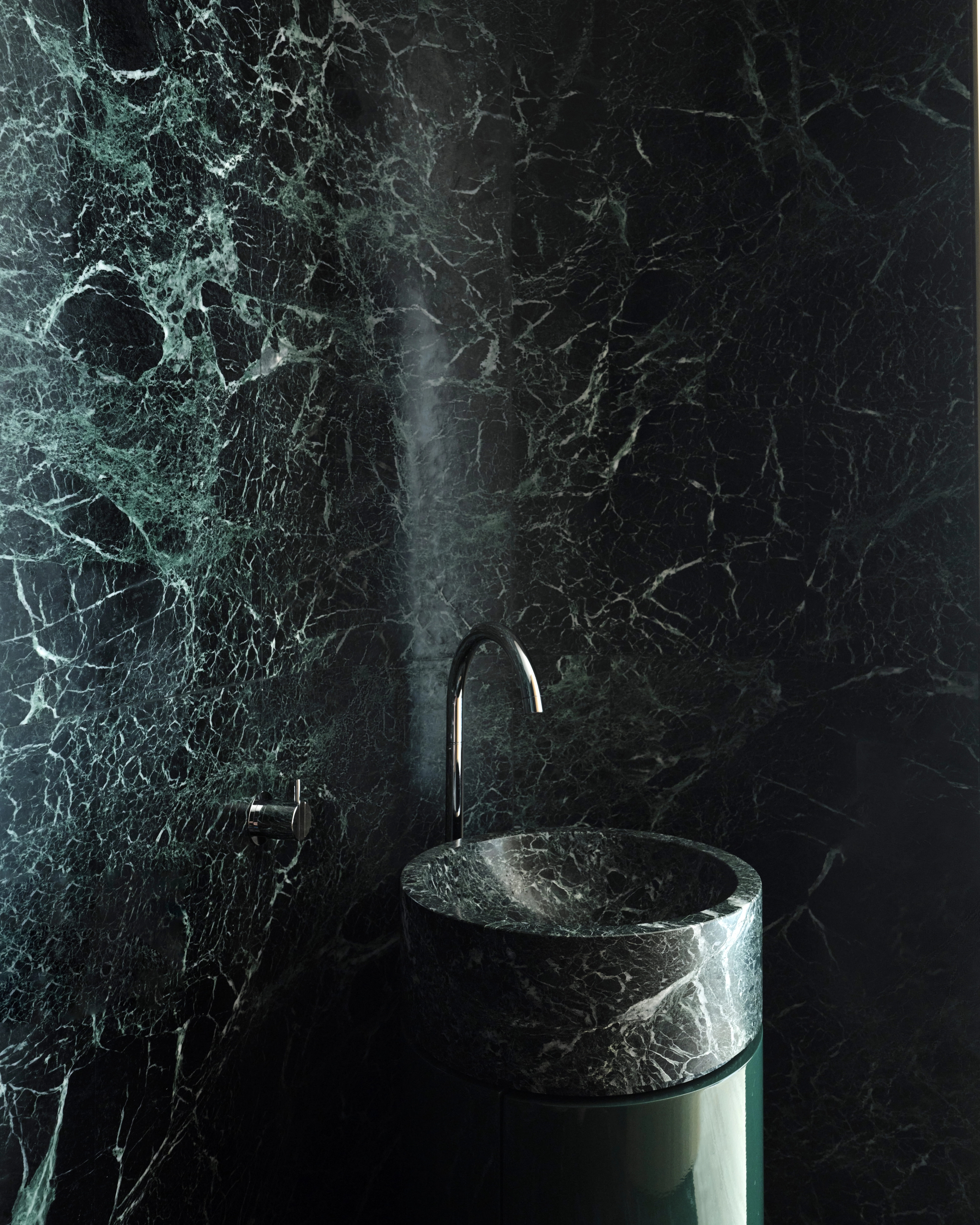 Dramatic green-marble bathroom with a monolithic basin in a Sydney CBD home