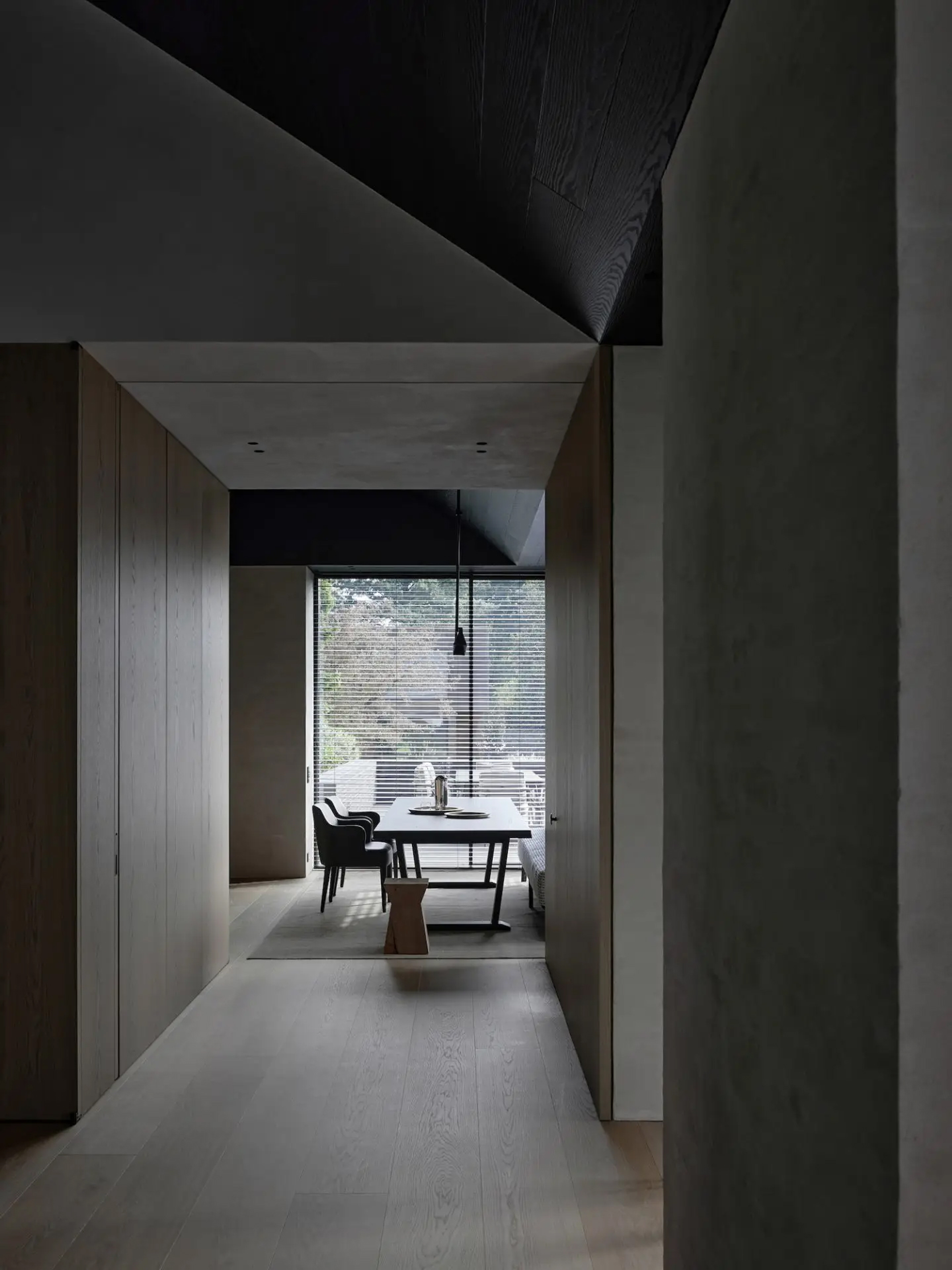 Dark, minimalist corridor in Vincent Van Duysen's B Residence opening to a dining space