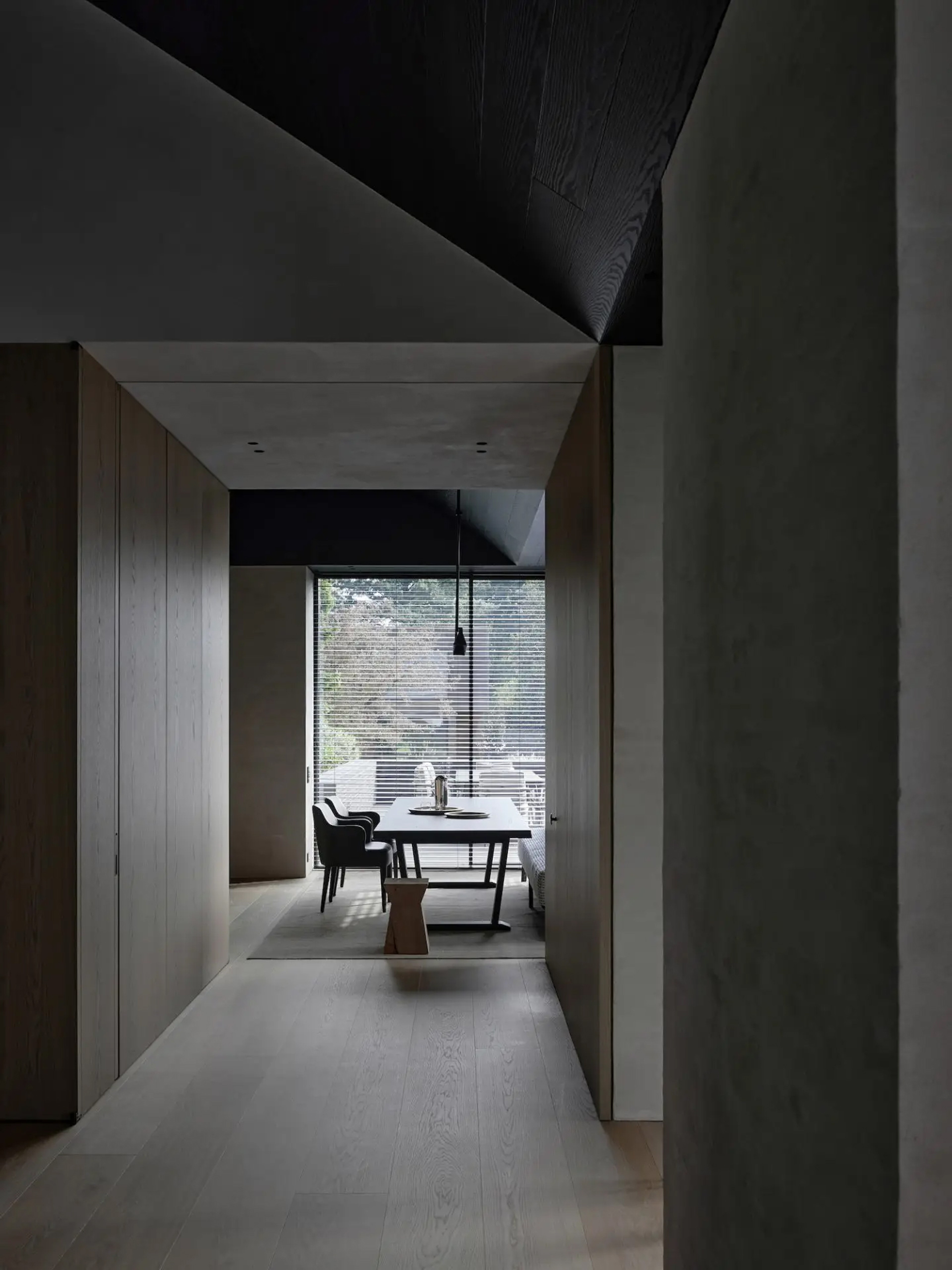 Dark, minimalist corridor in Vincent Van Duysen's B Residence opening to a dining space
