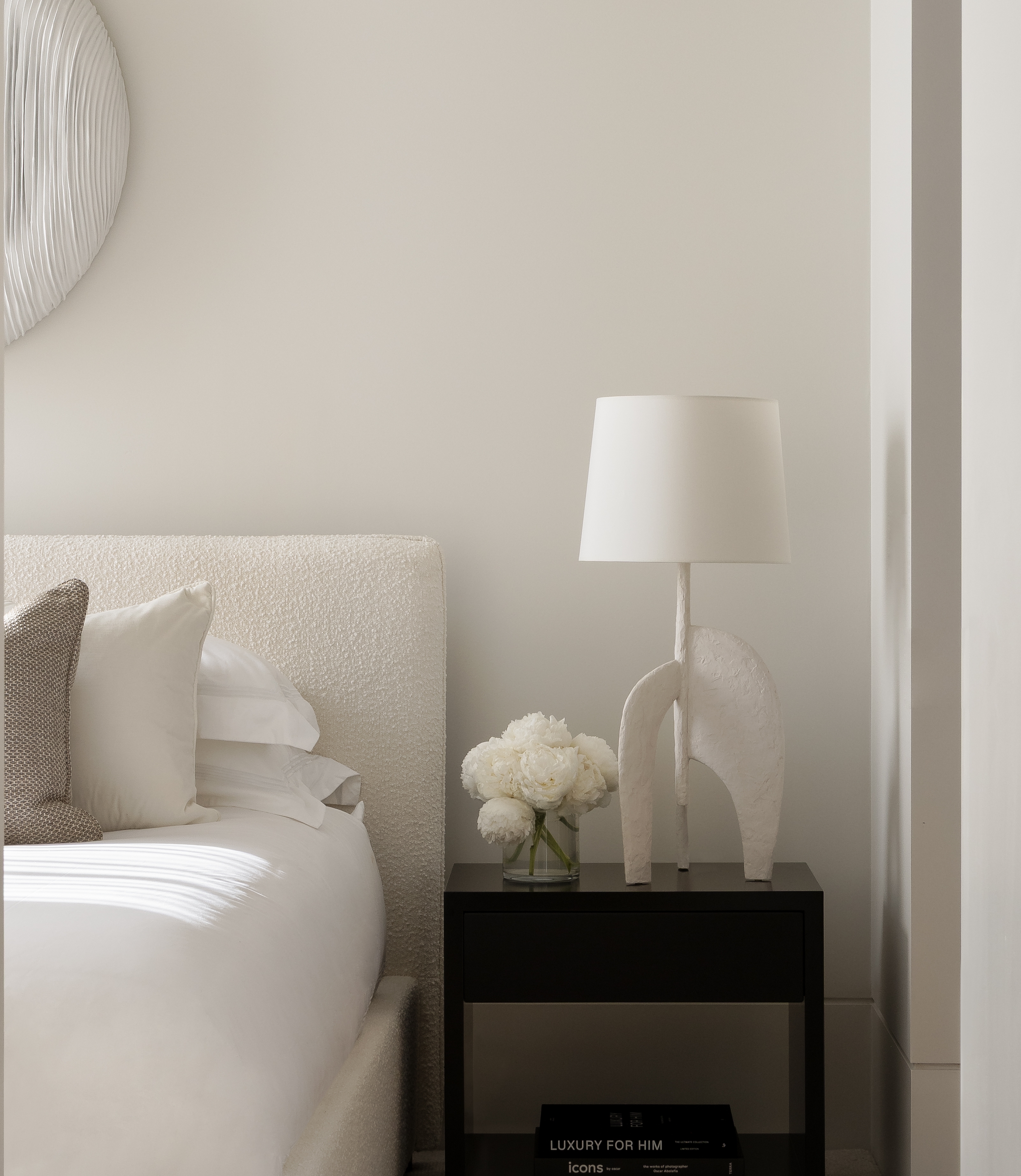 Glimpse through a doorway to a softly neutral bedroom with a bedside lamp