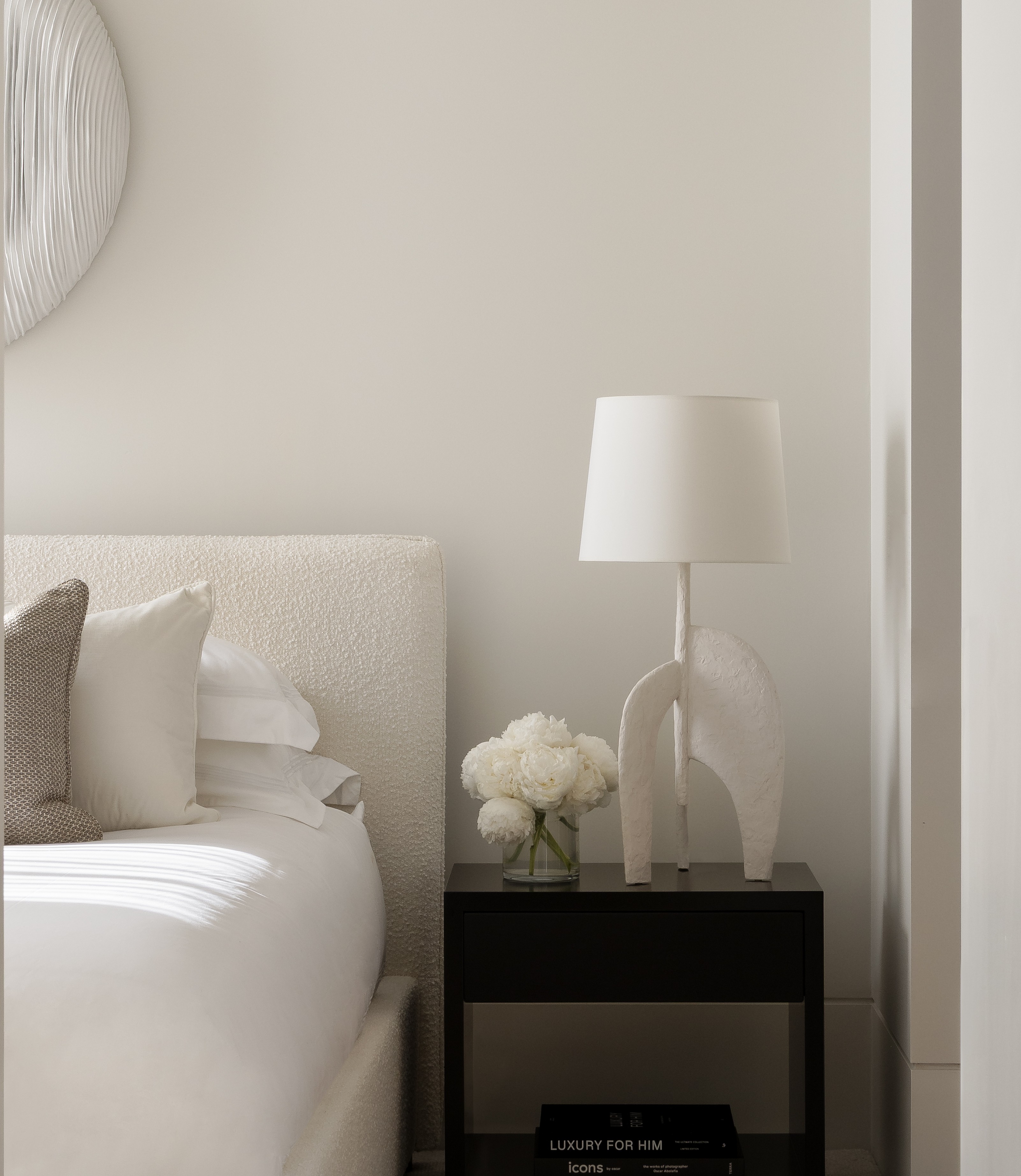 Glimpse through a doorway to a softly neutral bedroom with a bedside lamp