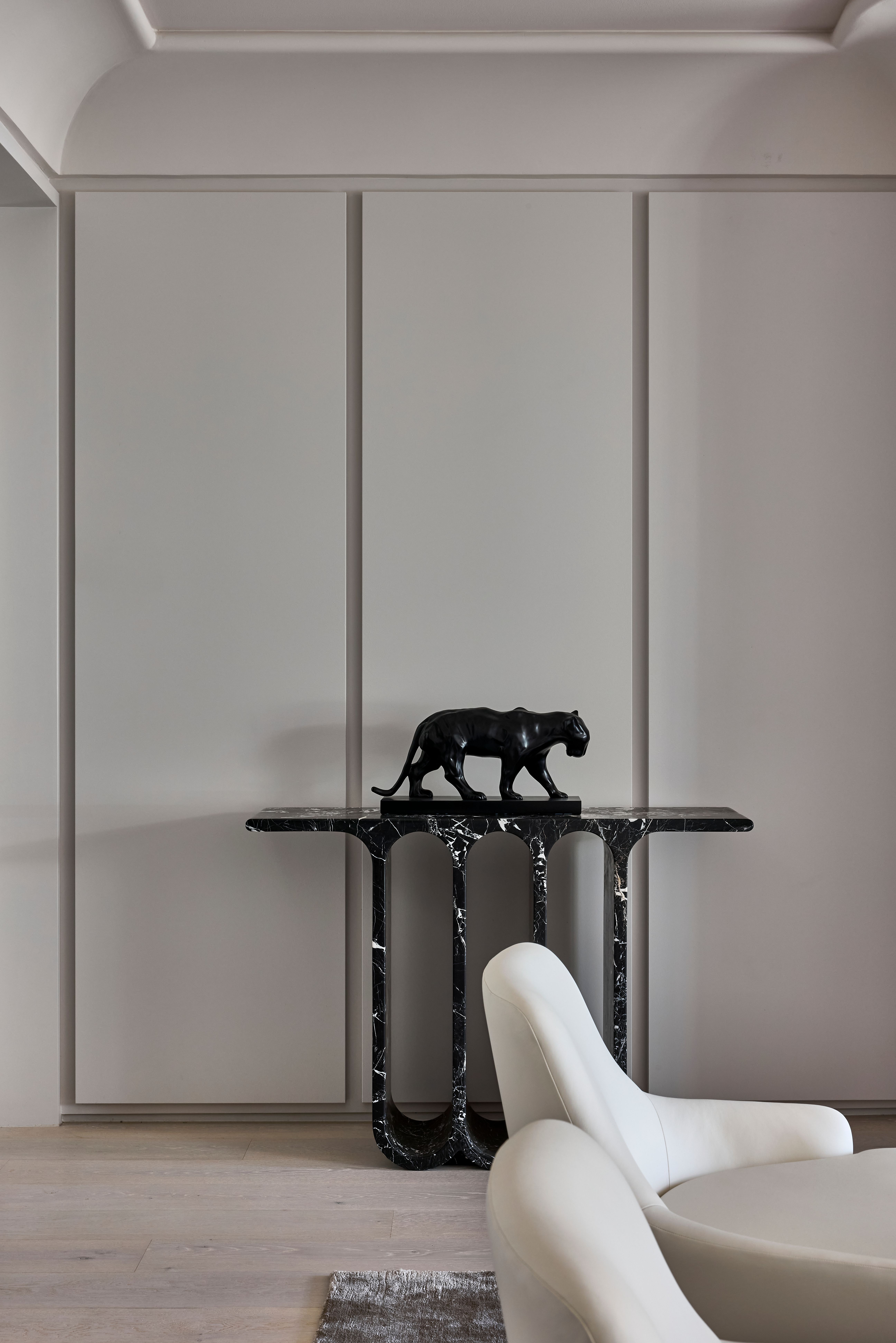 Black marble console with panther sculpture beside a bouclé swivel chair