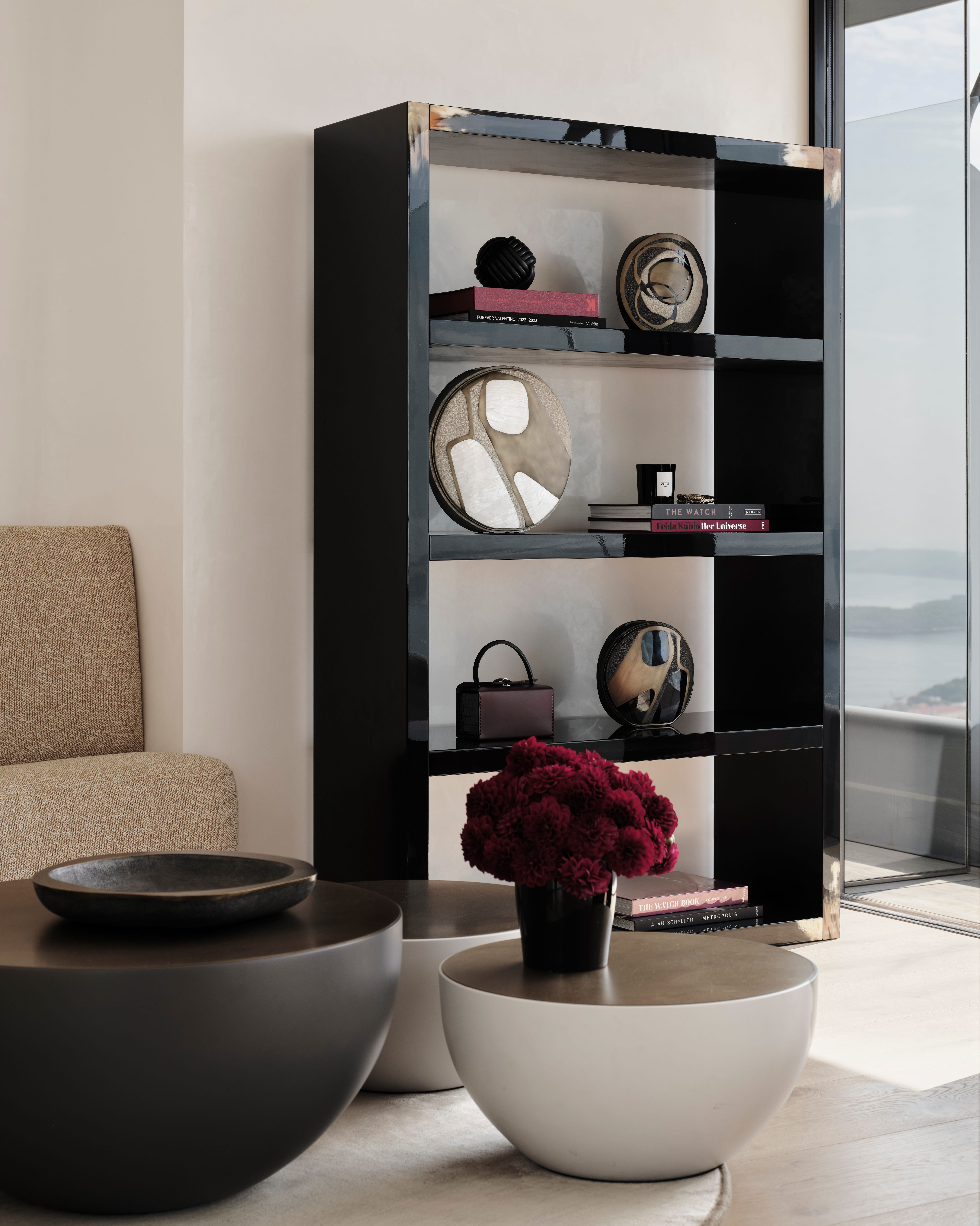 Black modular shelving styled with books and red roses above sculptural bowls in a bright room
