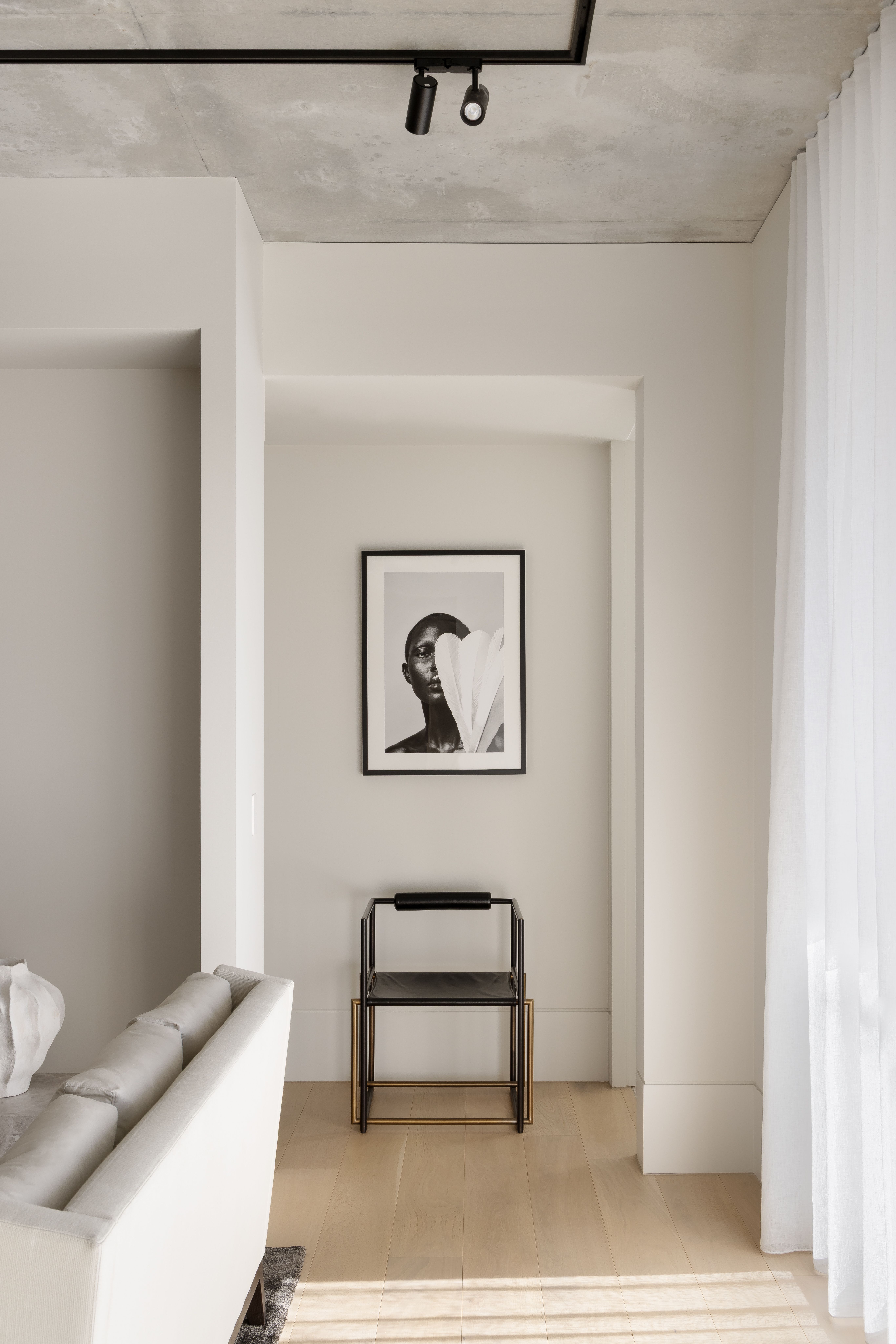 Serene corridor leading to a framed artwork above a slender black chair