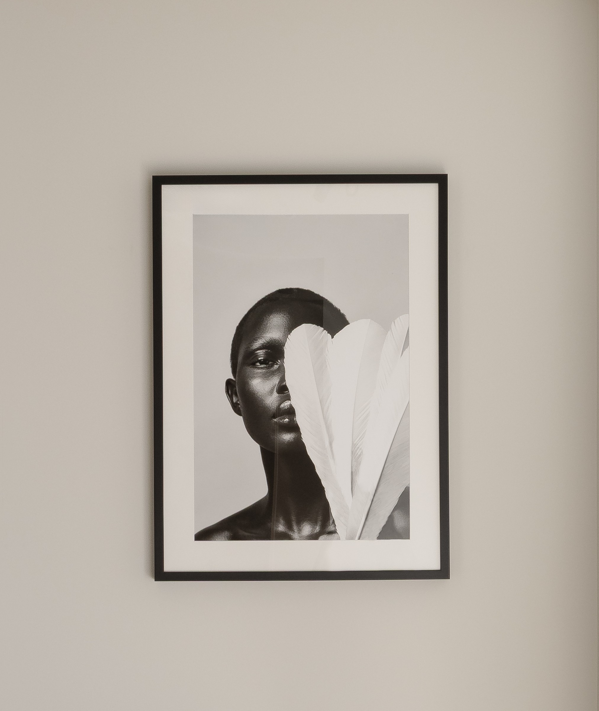 Serene corridor leading to a framed artwork above a slender black chair
